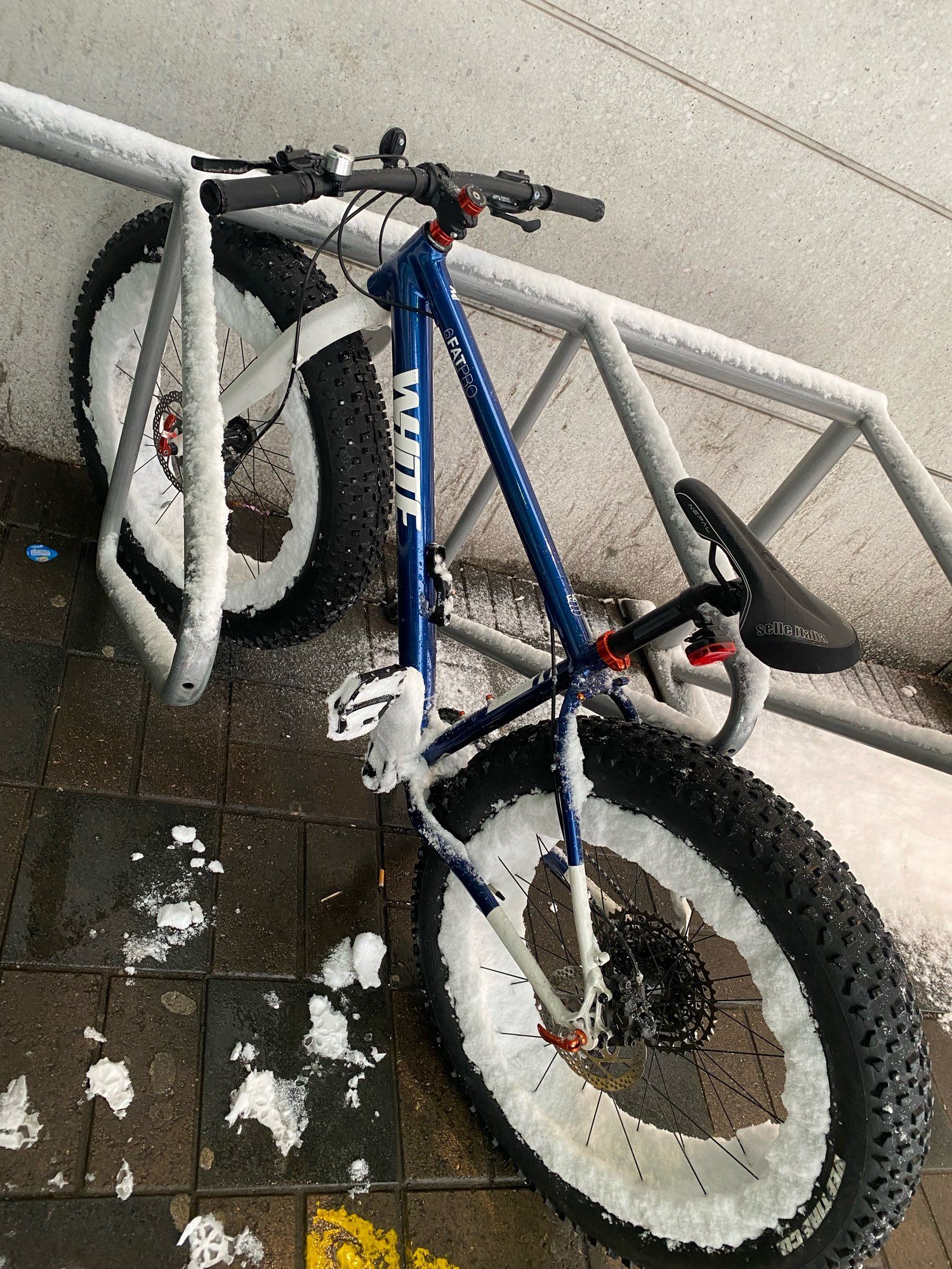 Fatbike vanteet lumisena kaupan telineellä