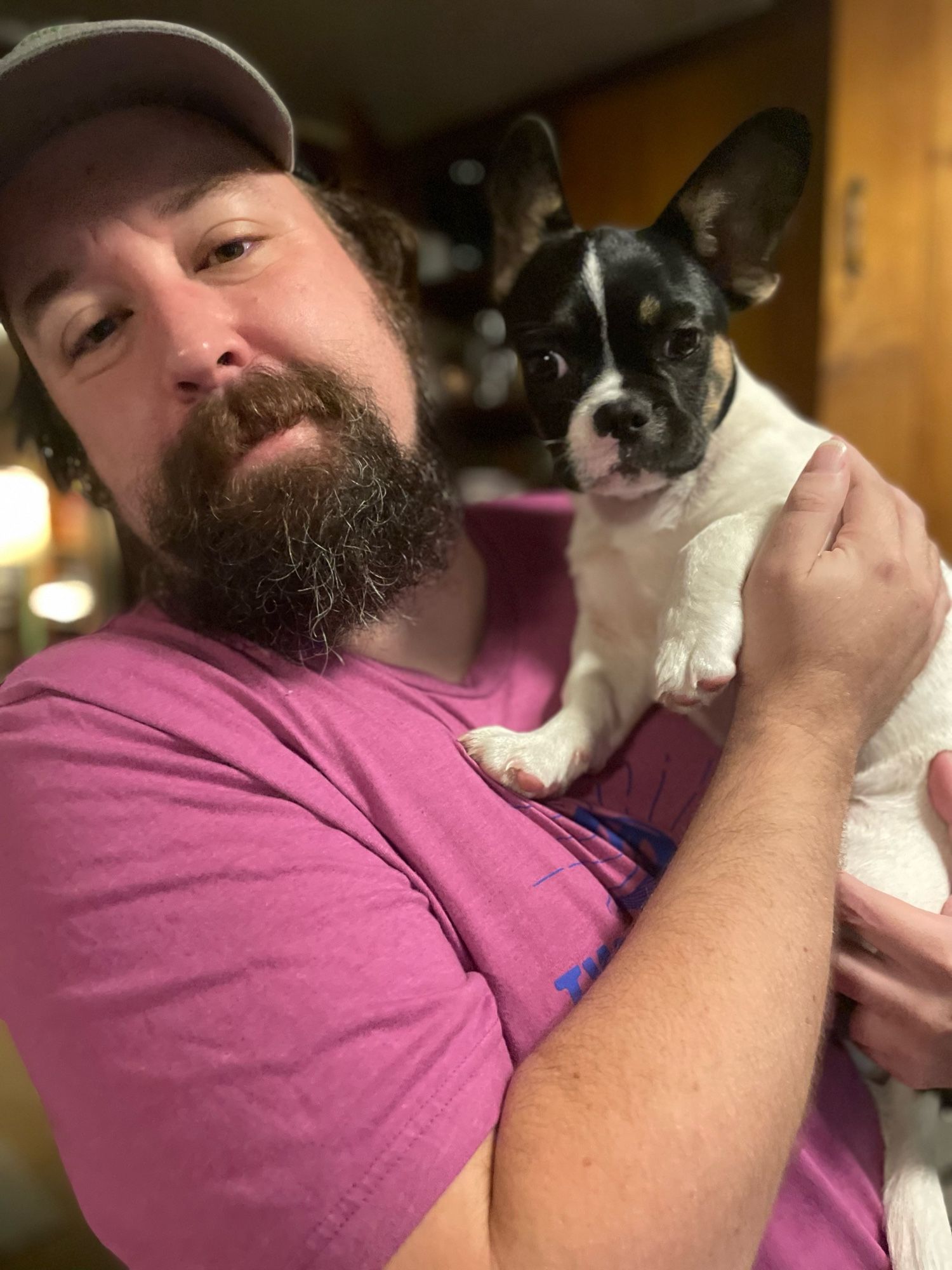 Michael standing in his kitchen holding up Bisou, a 4 1/2 month old French bulldog mix