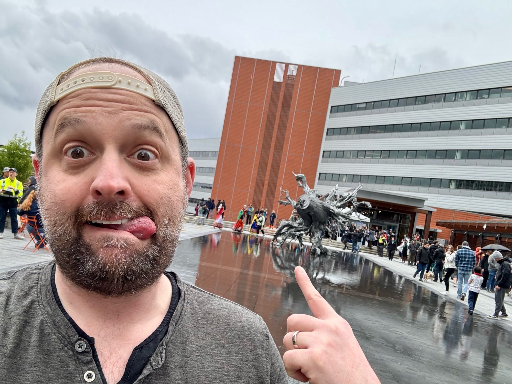 Handsome gay man in the rain pointing at a statue in reverse