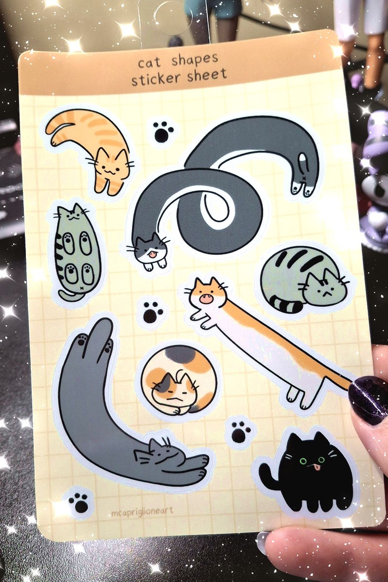 image of someone holding a 4x6 sticker sheet of cats in different shapes