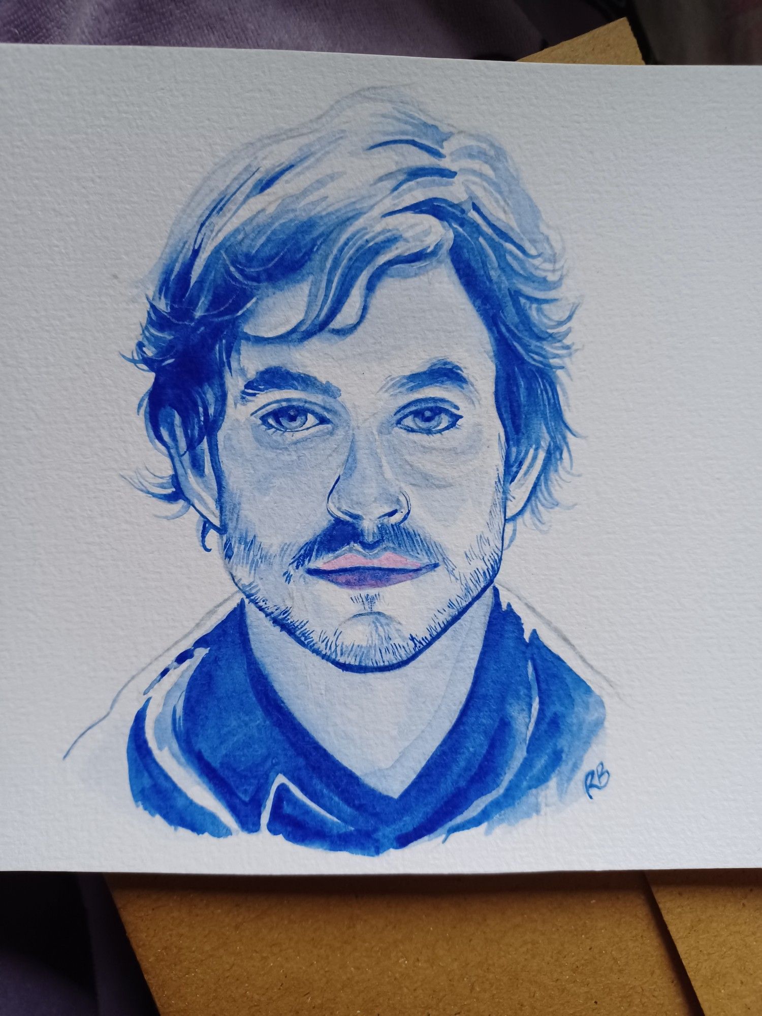 Blue watercolour painting of Will Graham on paper. His hair is ruffled and barely visible where the light touches it. His lips are a very light pink.