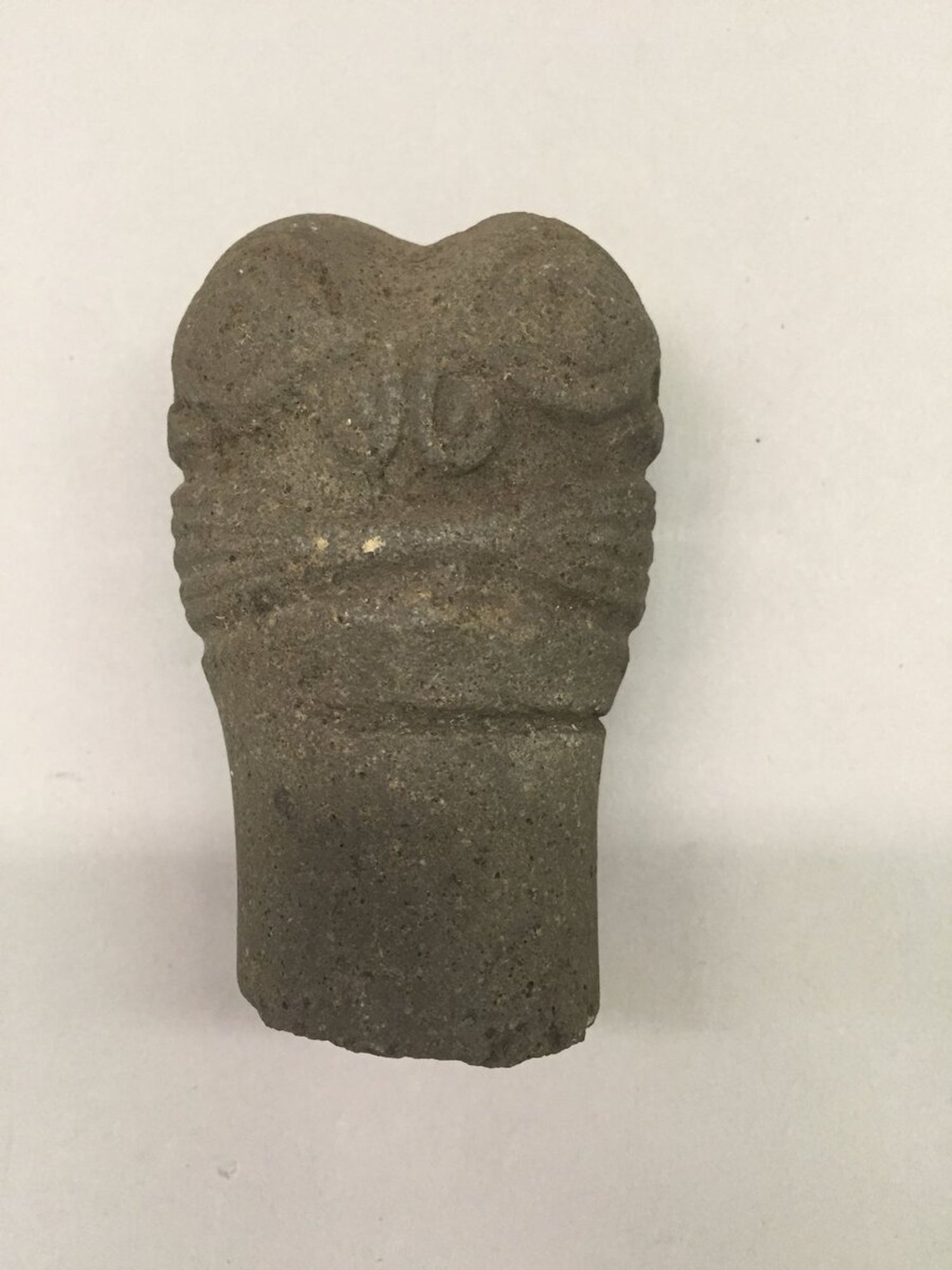 Stone head of poi pounder with carving showing double tiki.

