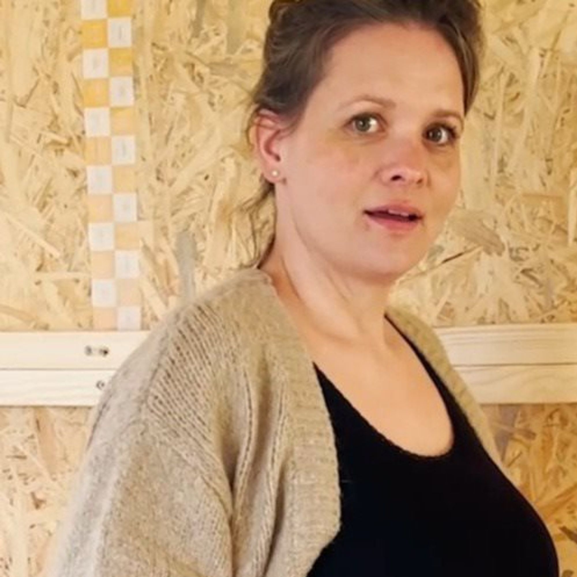 Ungeschminkt und unvorbereitet auf der Baustelle in vegane Strickjacke und Tanktop.