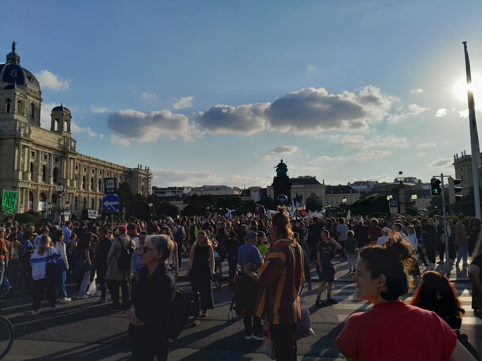 Blick auf die Schlusskundgebung auf dem Maria Theresienplatz zwischen den Museen im Gegenlicht der Abendsonne.