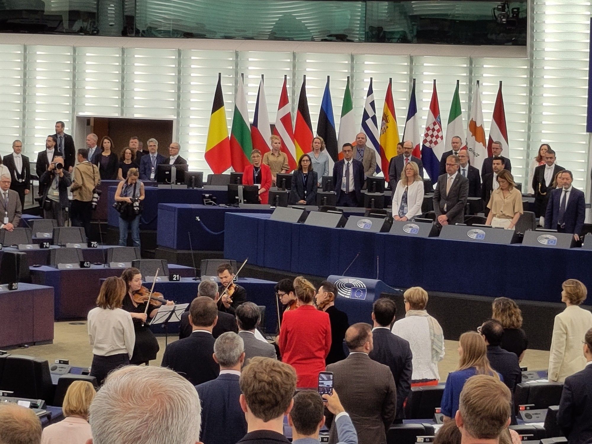 Streichquartett im Plenum des Europaparlaments, im Hintergrund das Präsidium, im Vordergrund stehende Abgeordnete