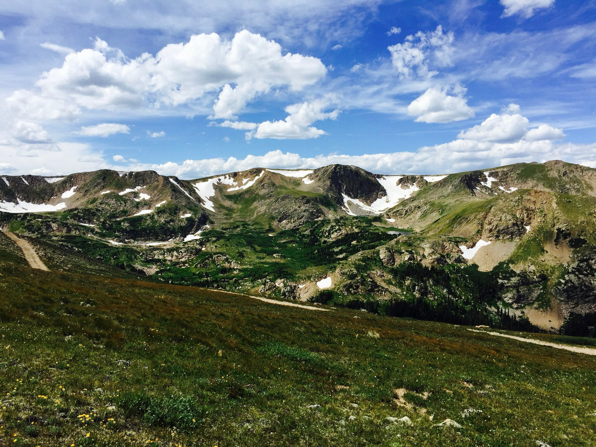 Rocky Mountains with snow field and meadows. A breeze blows from the west yet the air is pleasant and not chilly. One has no cares here. 