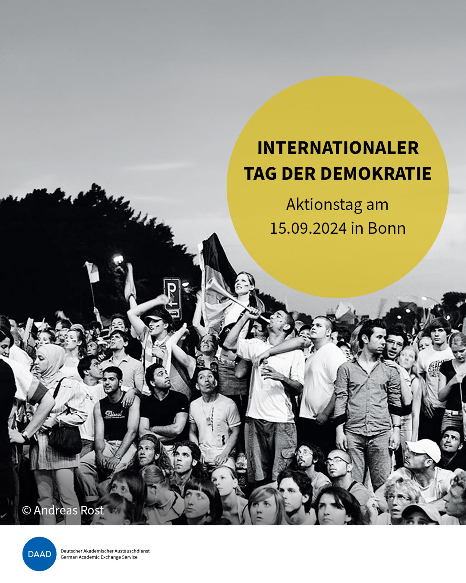 Auf einem Platz ist eine Menge diverser Menschen versammelt. Eine Frau hält eine Deutschlandfahne. Etwa wie beim Public Viewing. Ein Störer zeigt den Titel: Internationaler Tag der Demokratie: Aktionstag am 15.09.2024 in Bonn. Bildquelle: Andreas Rost