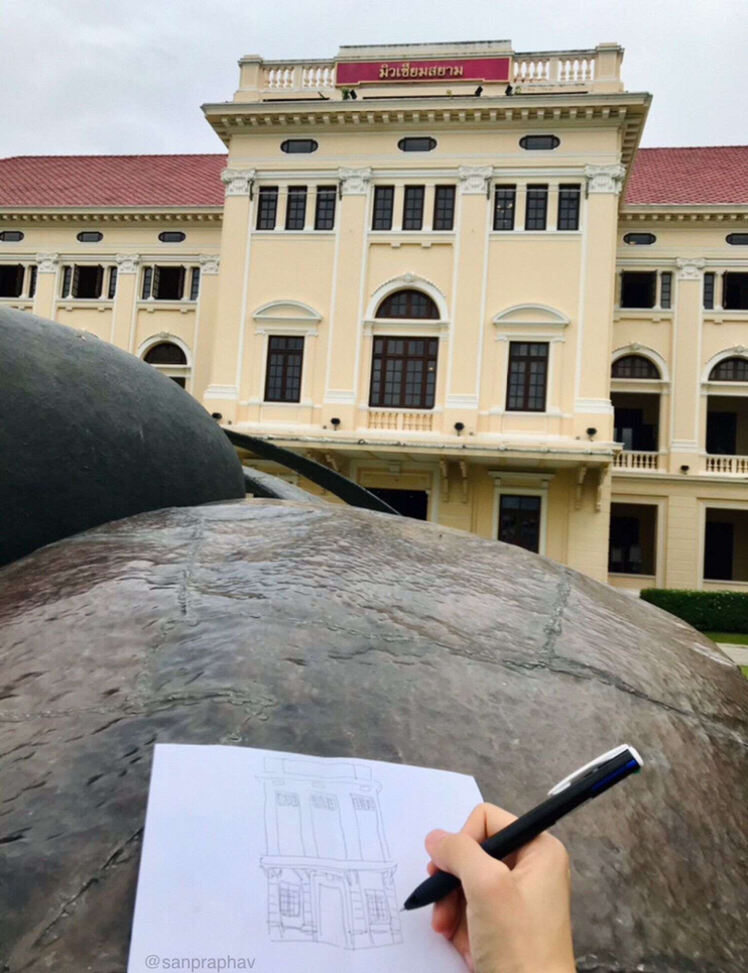 A photograph of my hand sketching Museum Siam main building