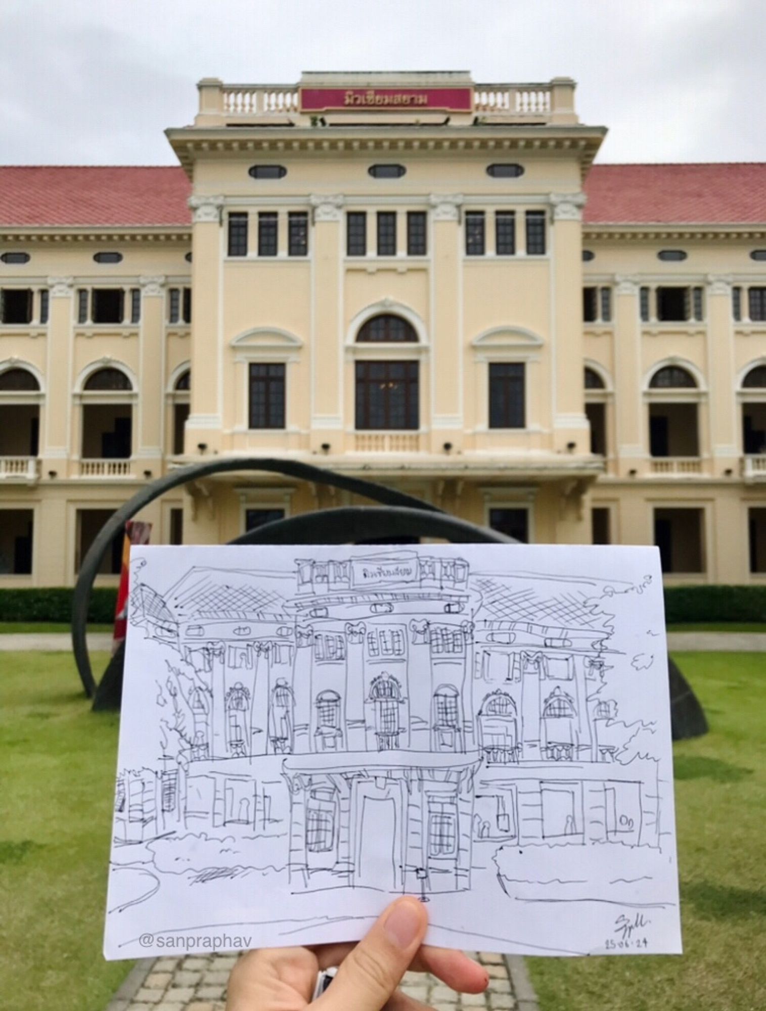 A photograph of my hand holding my sketch of Museum Siam main building