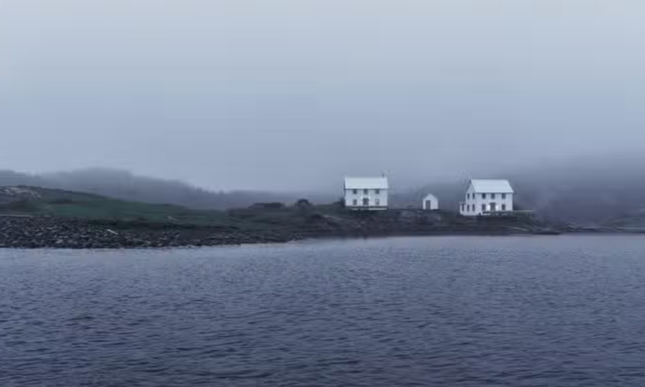 2 large white houses on a desolate island. The area is foggy.