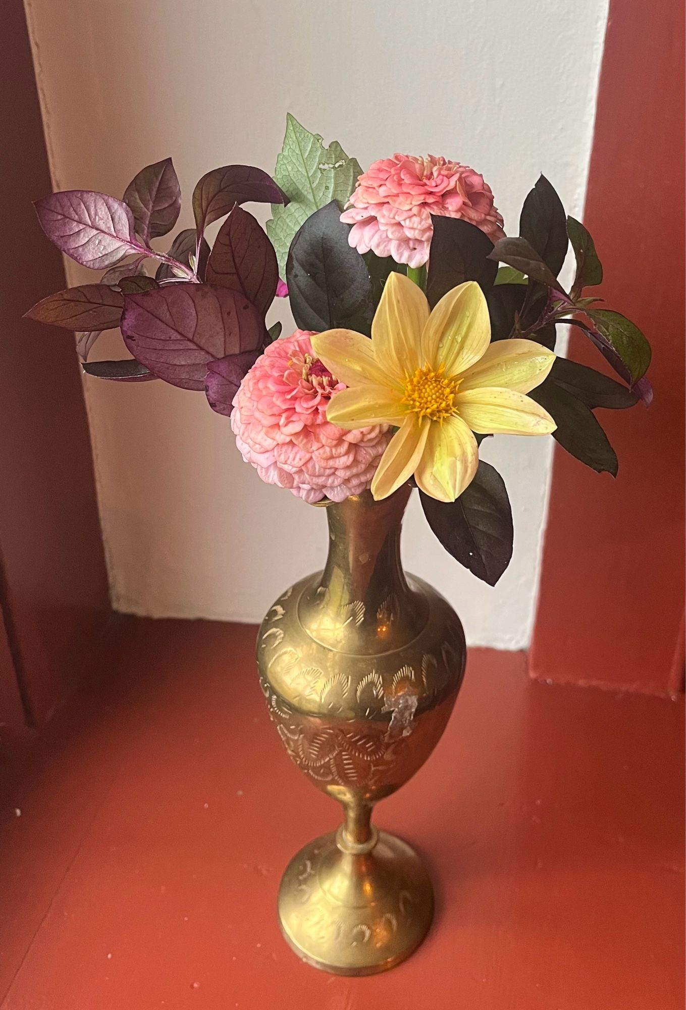 A gold vase with dahlias and zinnias