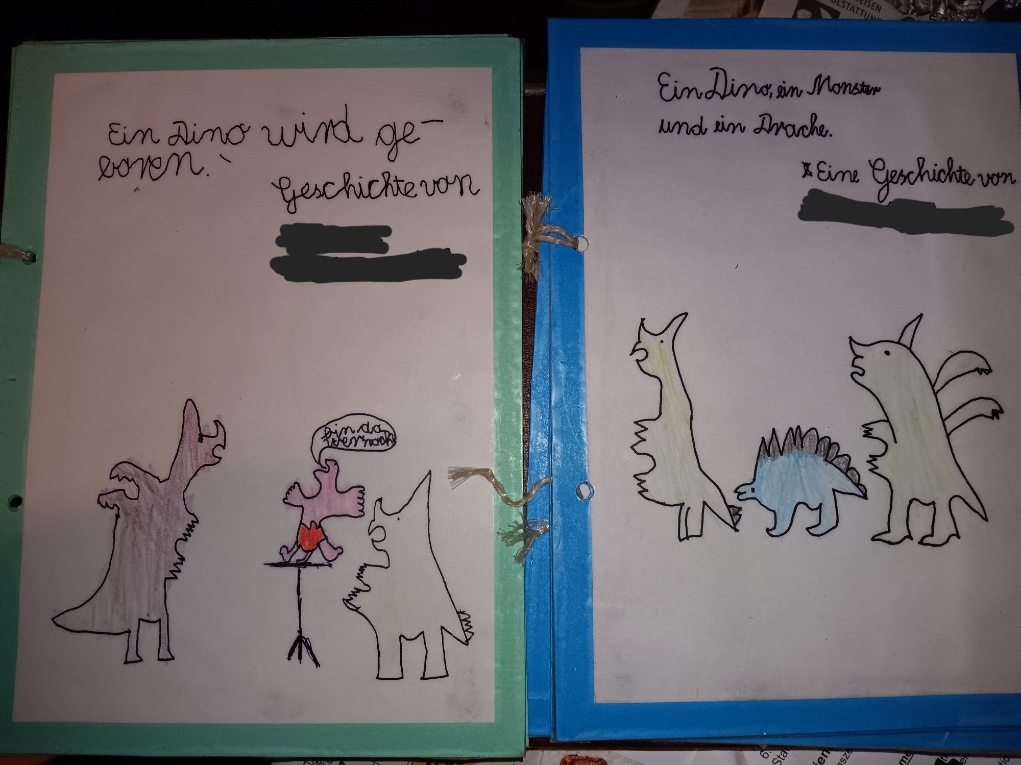 Zwei "Kinderbücher, gebastelt aus Zeichnungen auf Zeichenpapier, das auf Tonpapier in Türkis und Blau geklebt wurde, danach folgert und abschließend mit Schnur gebunden. Beide zeigen auf dem Cover einen Drachen, ein Monster (die beide verdächtig wie zweibeinige Ceratopside aussehen) und einen kleinen Dinosaurier, einmal ein rosa Baby das "Bin da, wer noch?" ruft, einmal ein kleiner blauer Stegosaurus. Buchtitel 1: EIN DINO WIRD GEBOREN. Buchtitel 2: EIN DINO, EIN MONSTER UND EIN DRACHE.