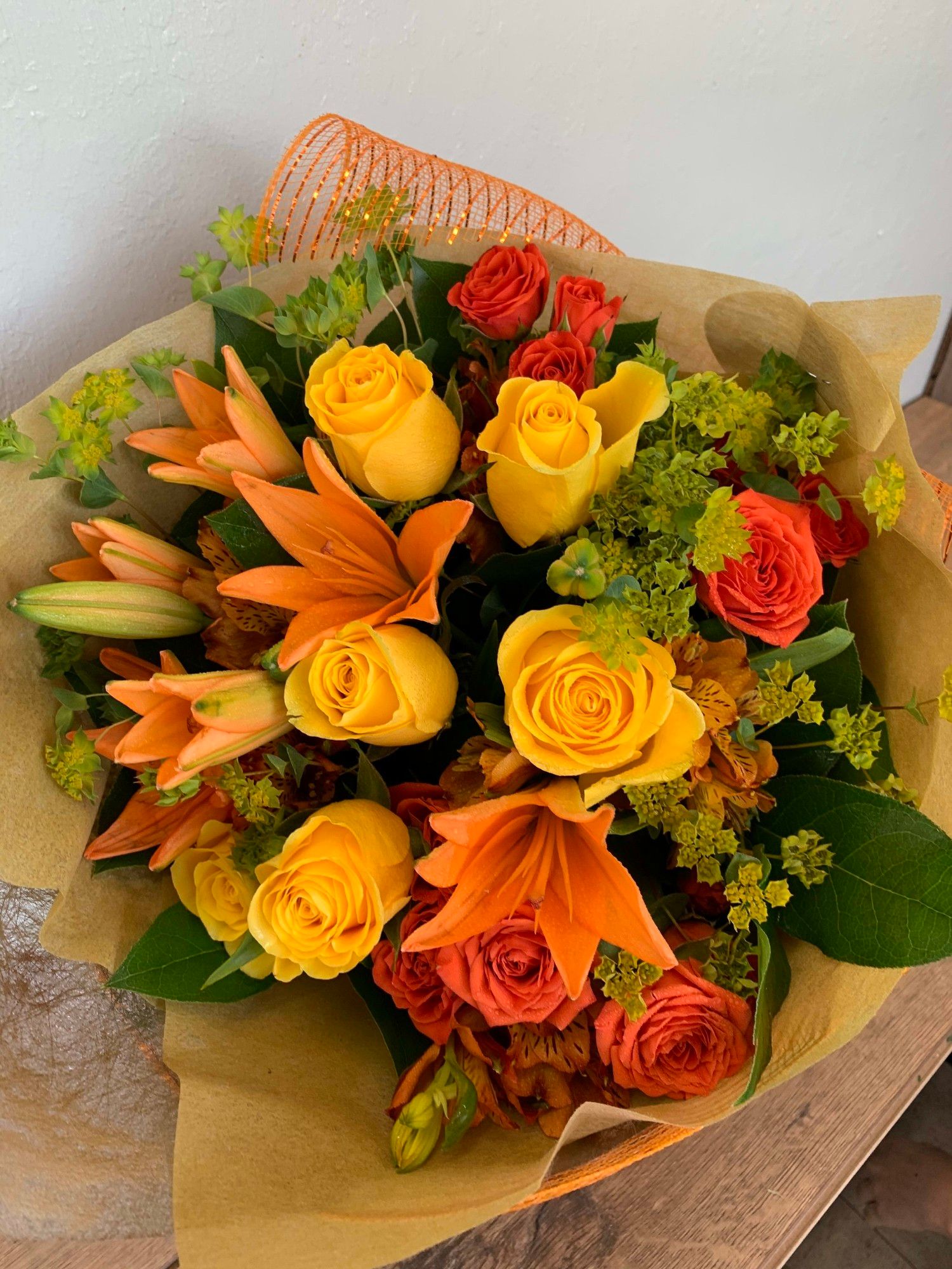 Bouquet of orange and yellow roses, orange lilies and green filler