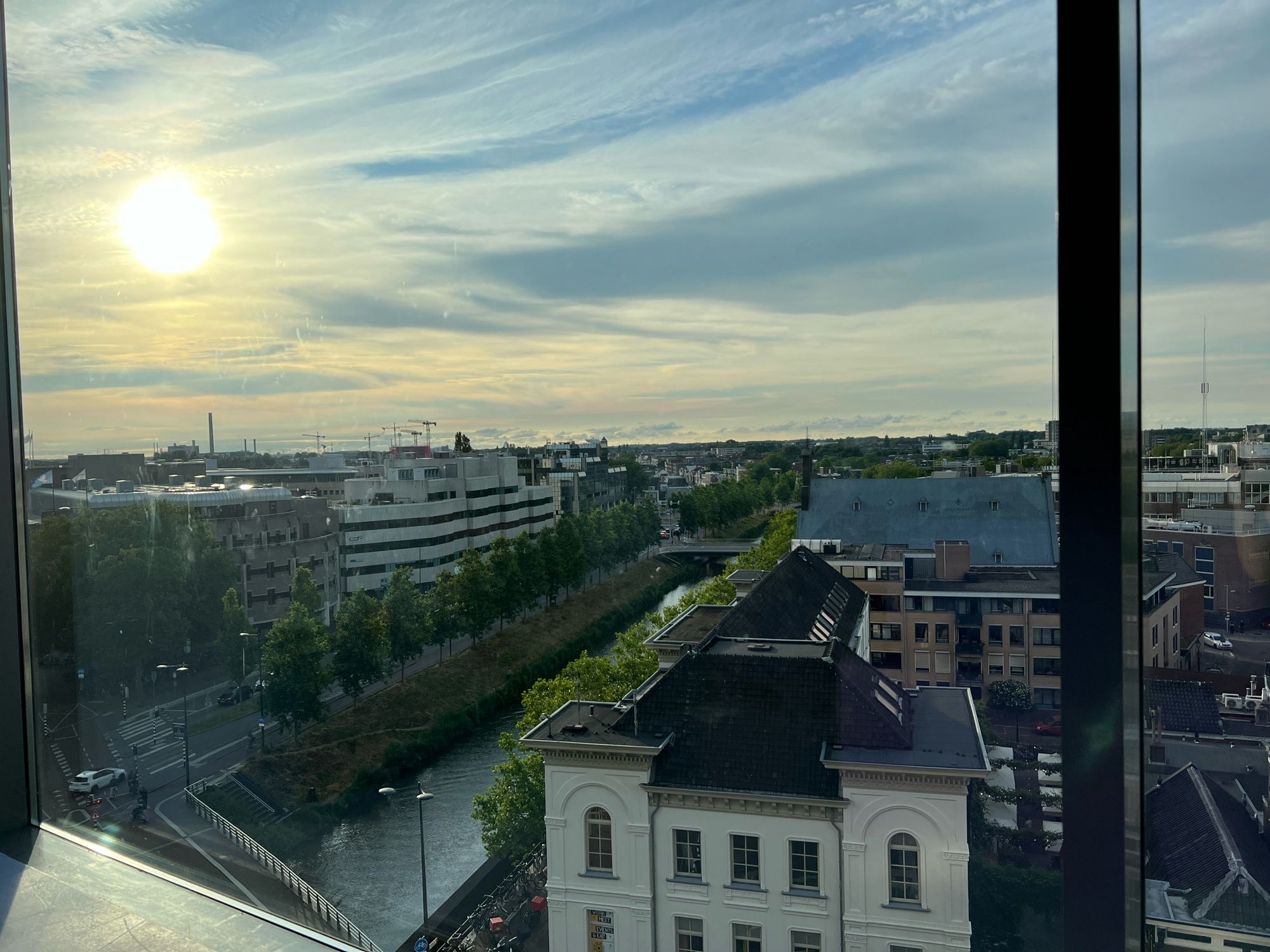 Je kijkt over de stad uit, de zon gaat links in beeld onder.