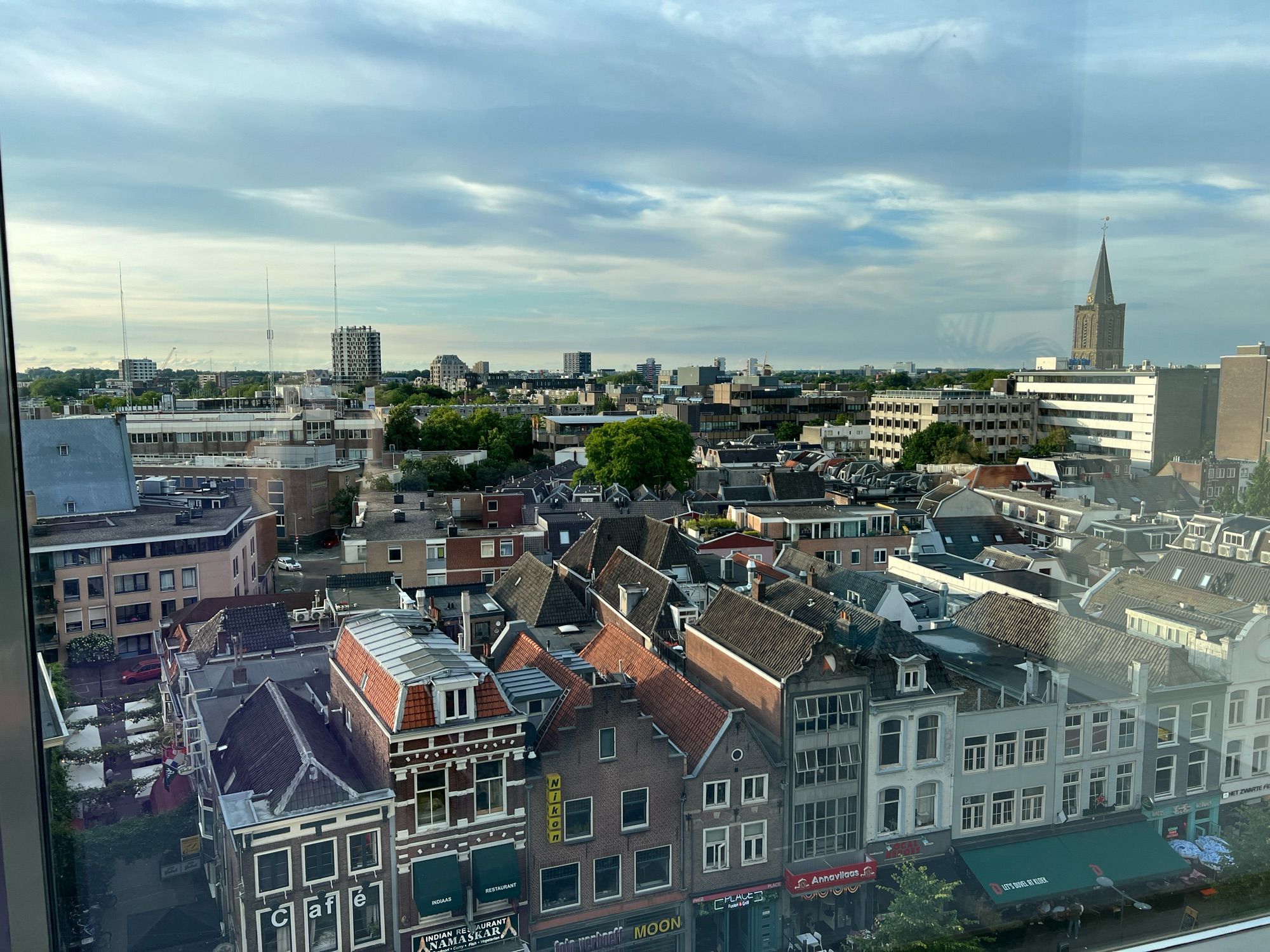 Uitzicht over Utrecht. In de verte een kerktoren en een molen.