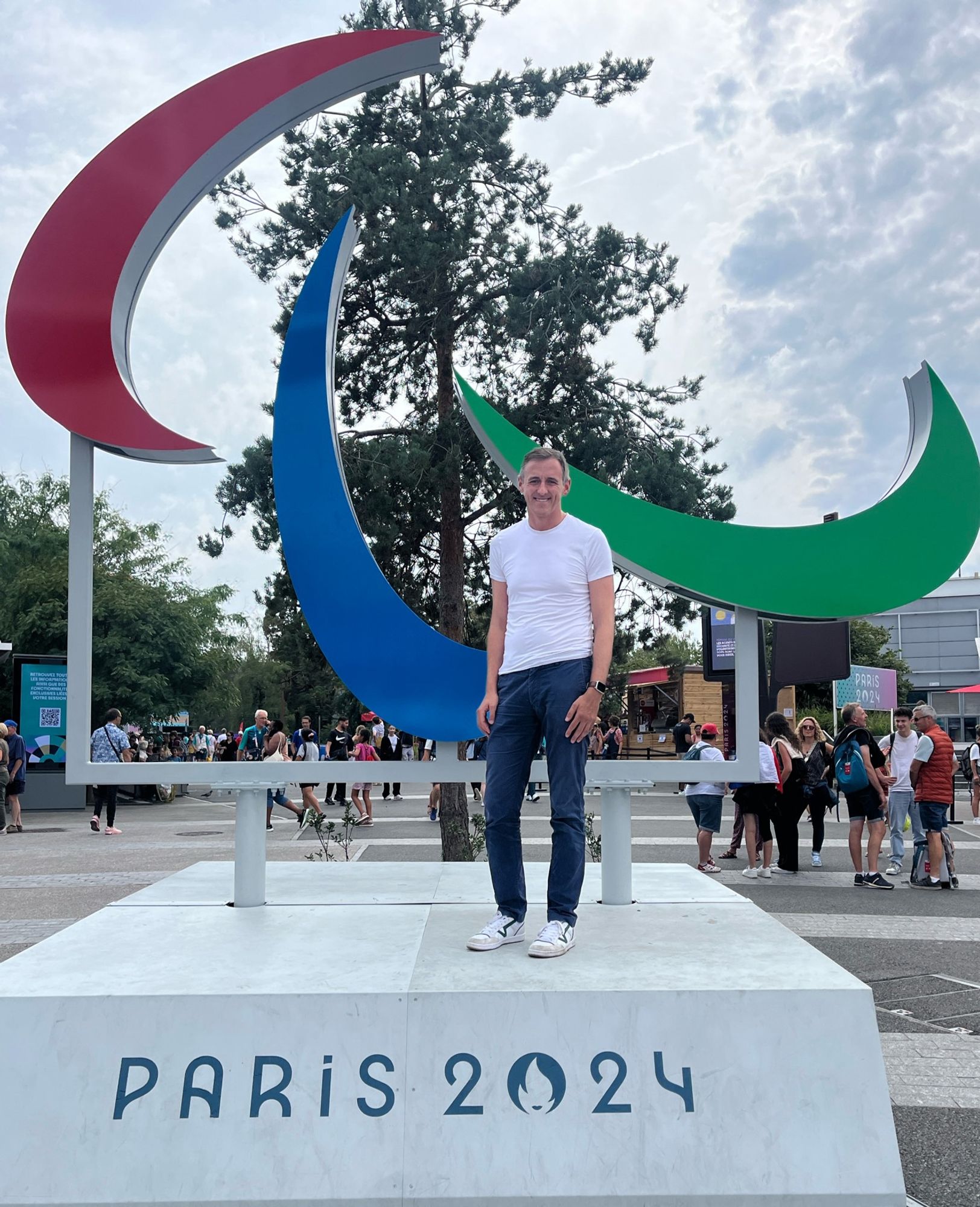 Lewis standing next to the Paris 2024 Paralympic symbol