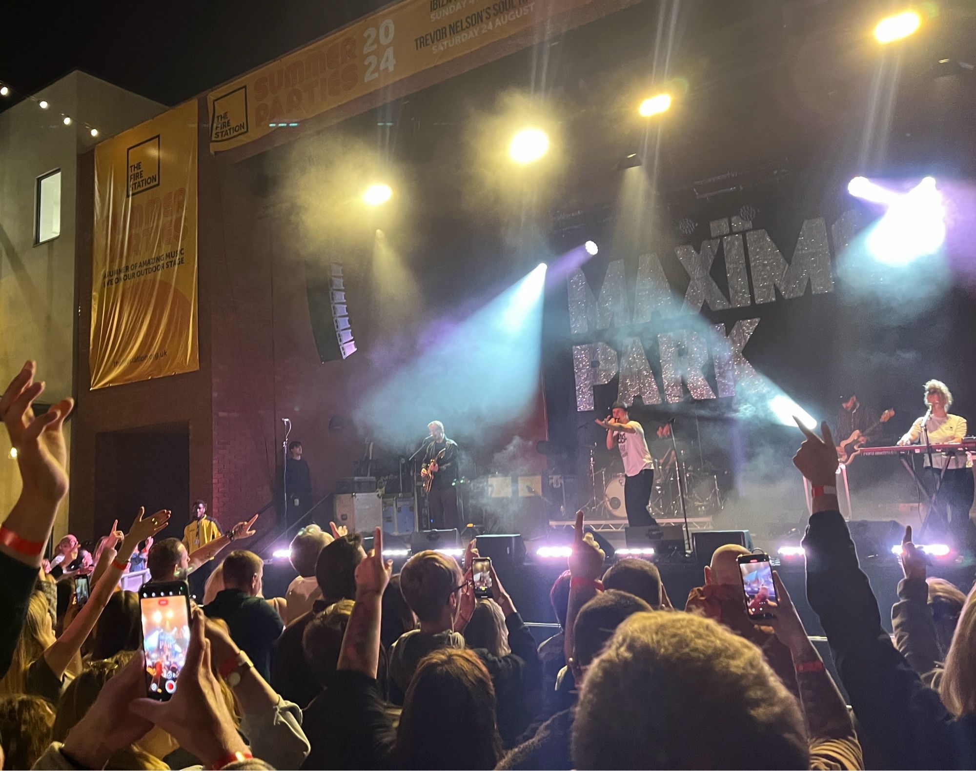 Maximo Park on stage playing to crowd with their hands in the air