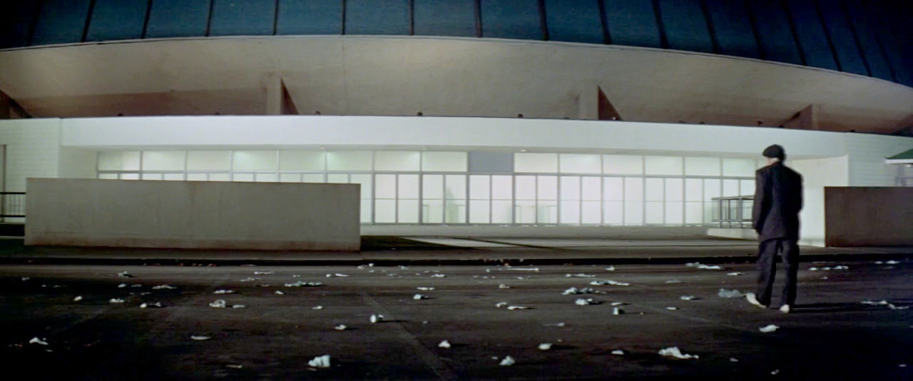 An old man walks across a trash-strewn parking lot toward the suicide center at the end of SOYLENT GREEN.