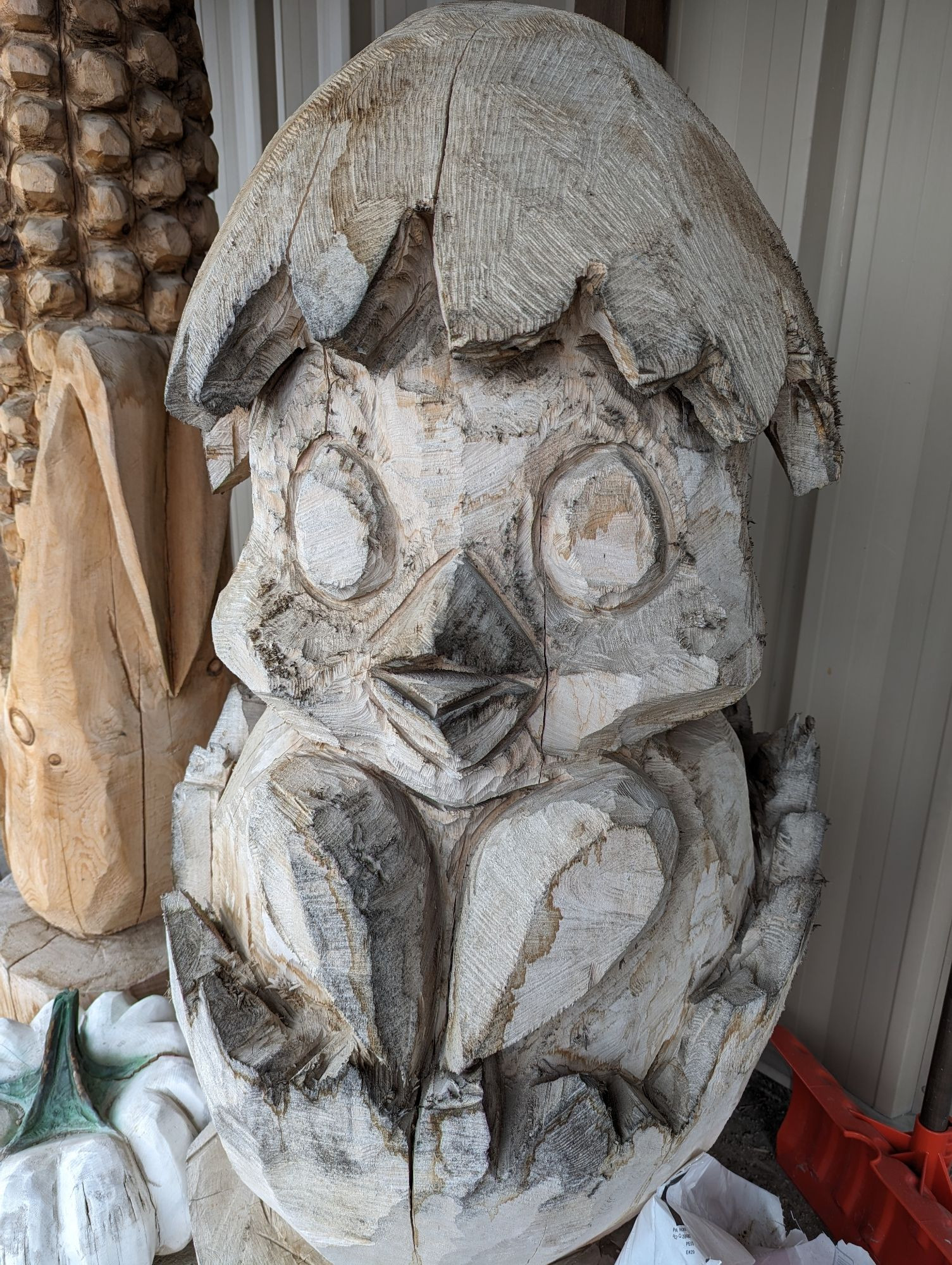 Wooden sculpture of a chick breaking out of its eggshell