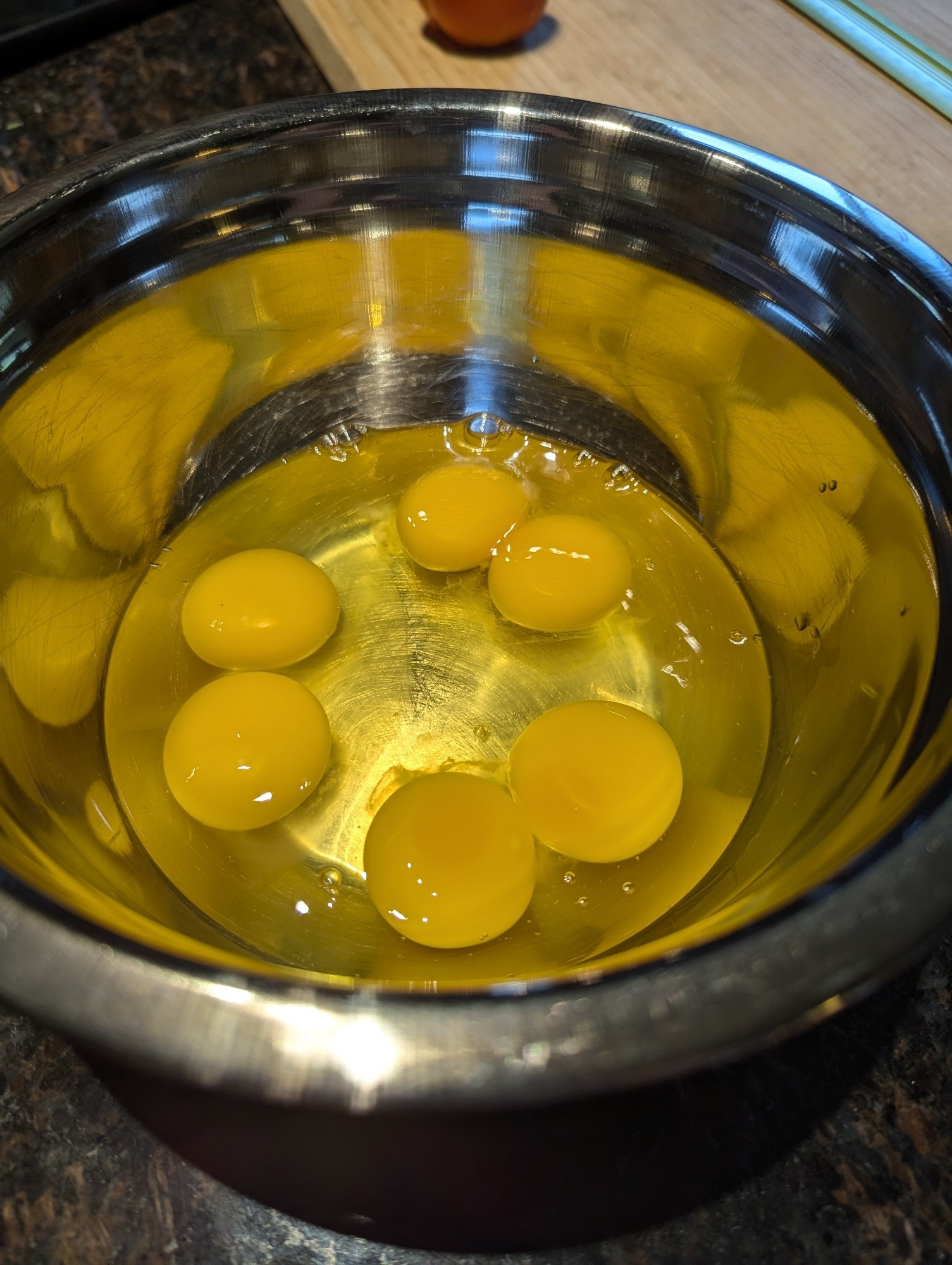 Six yolks in a metal bowl from three chicken eggs