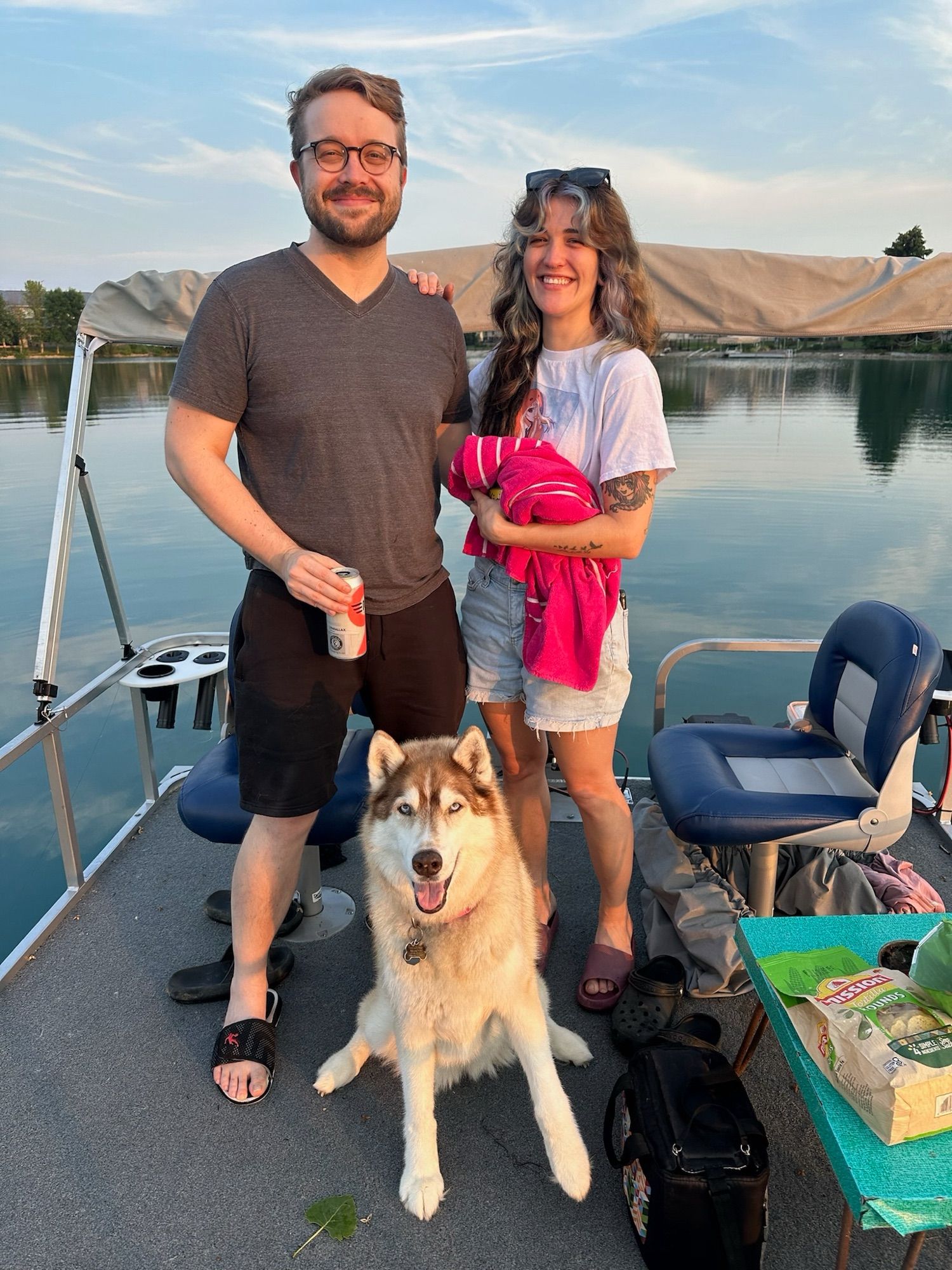 Picture of a dog, a man, and a woman smiling for a picture on a boat