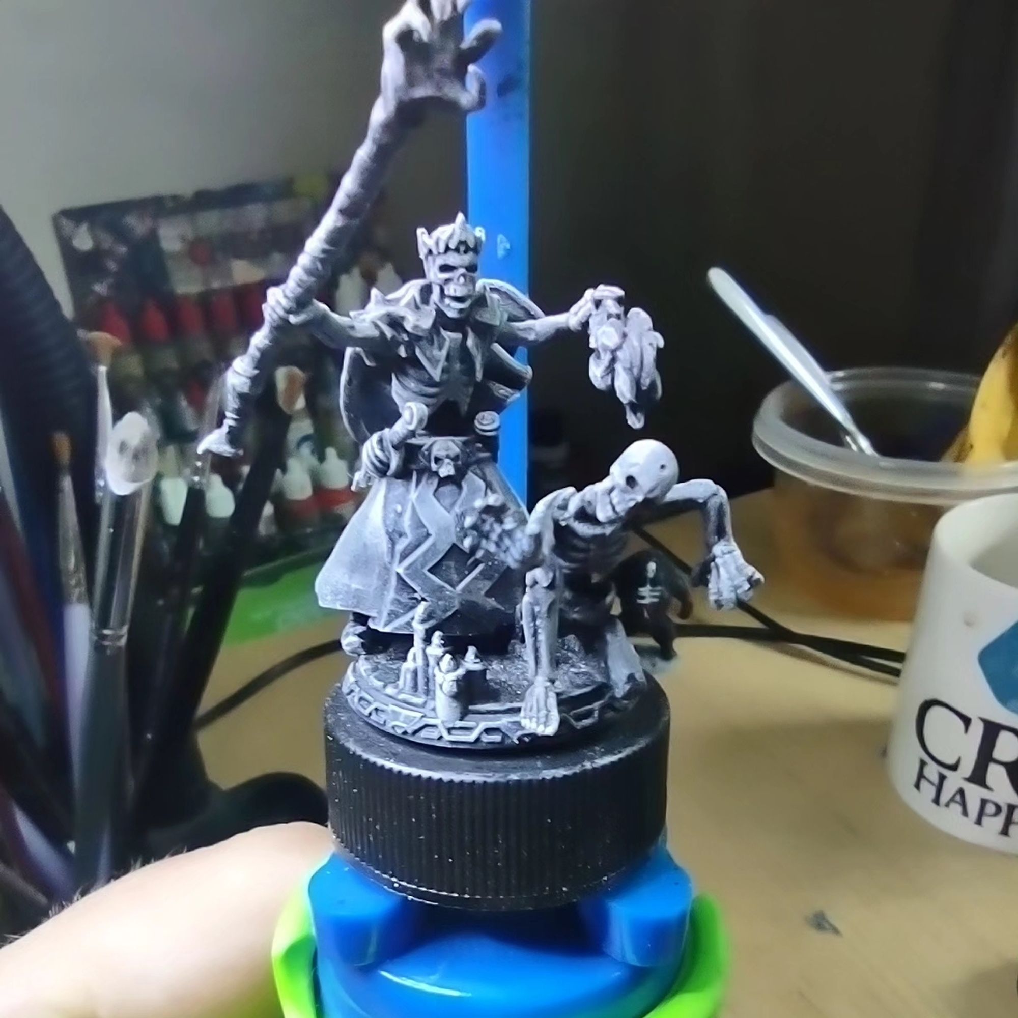 Miniature of a lich lord holding a staff with a clawed hand at the end summoning a skeleton