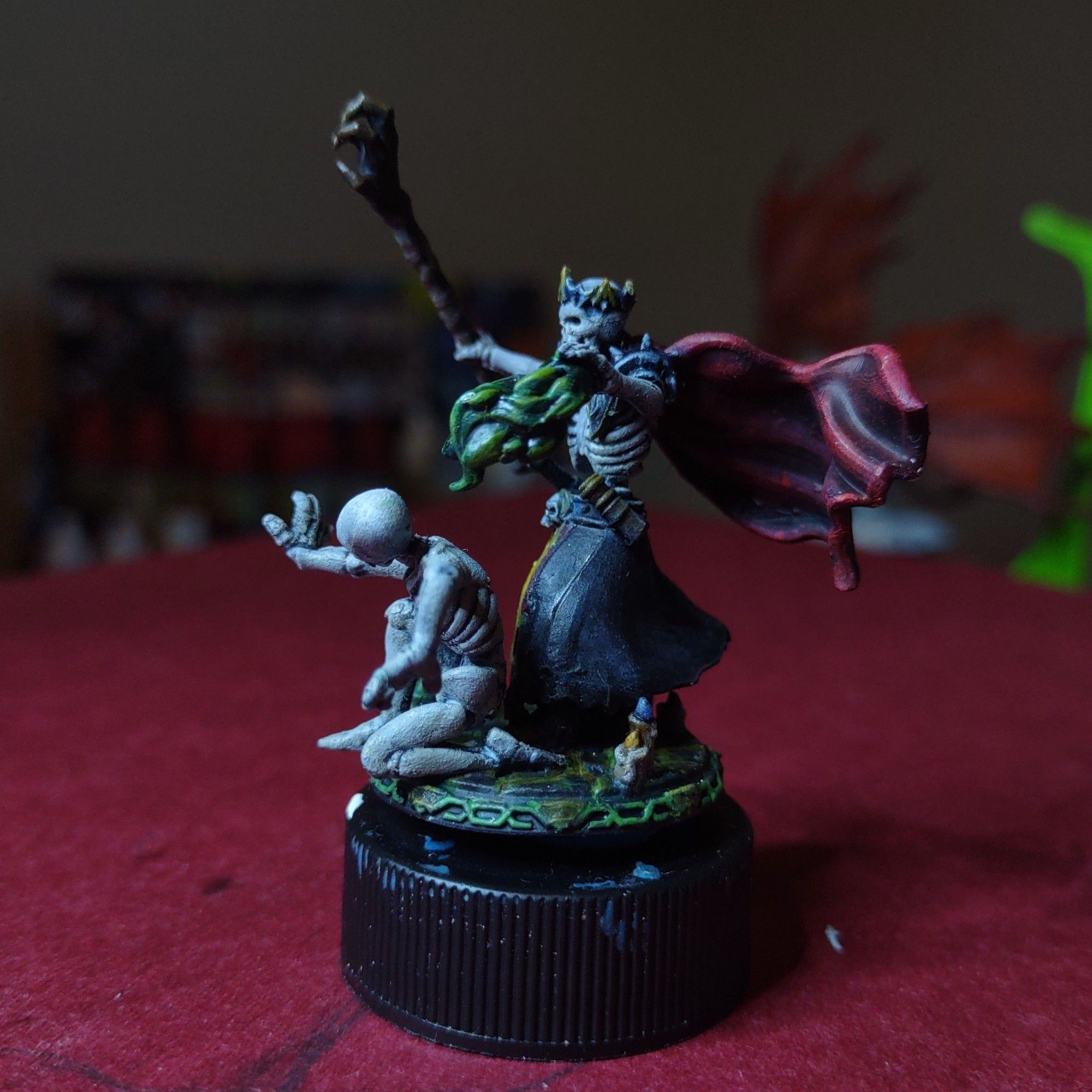 A miniature of a lich holding a claw shaped staff, candles on the ground, and a spell effect summoning a skeleton