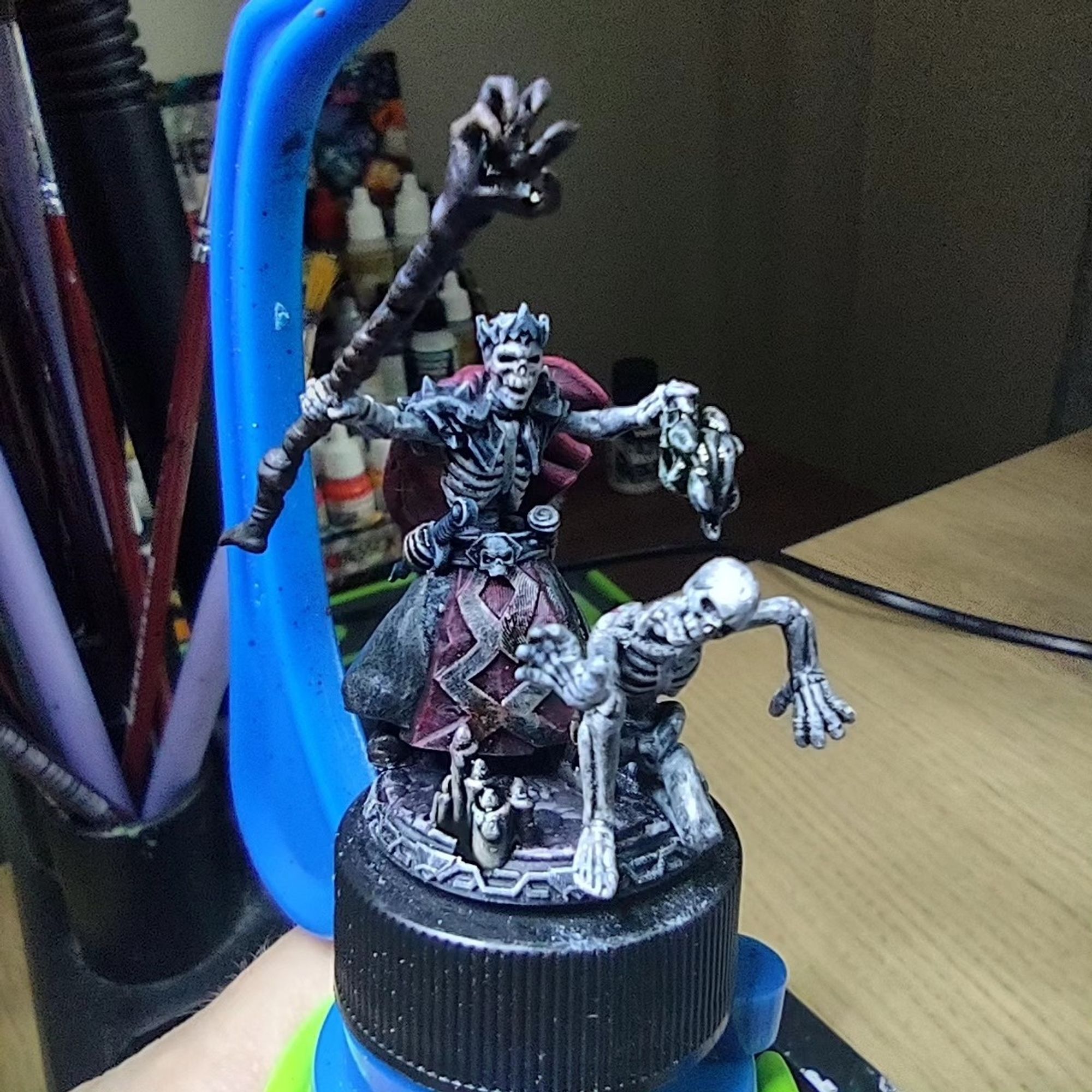 Miniature of a lich lord holding a staff with a clawed hand at the end summoning a skeleton