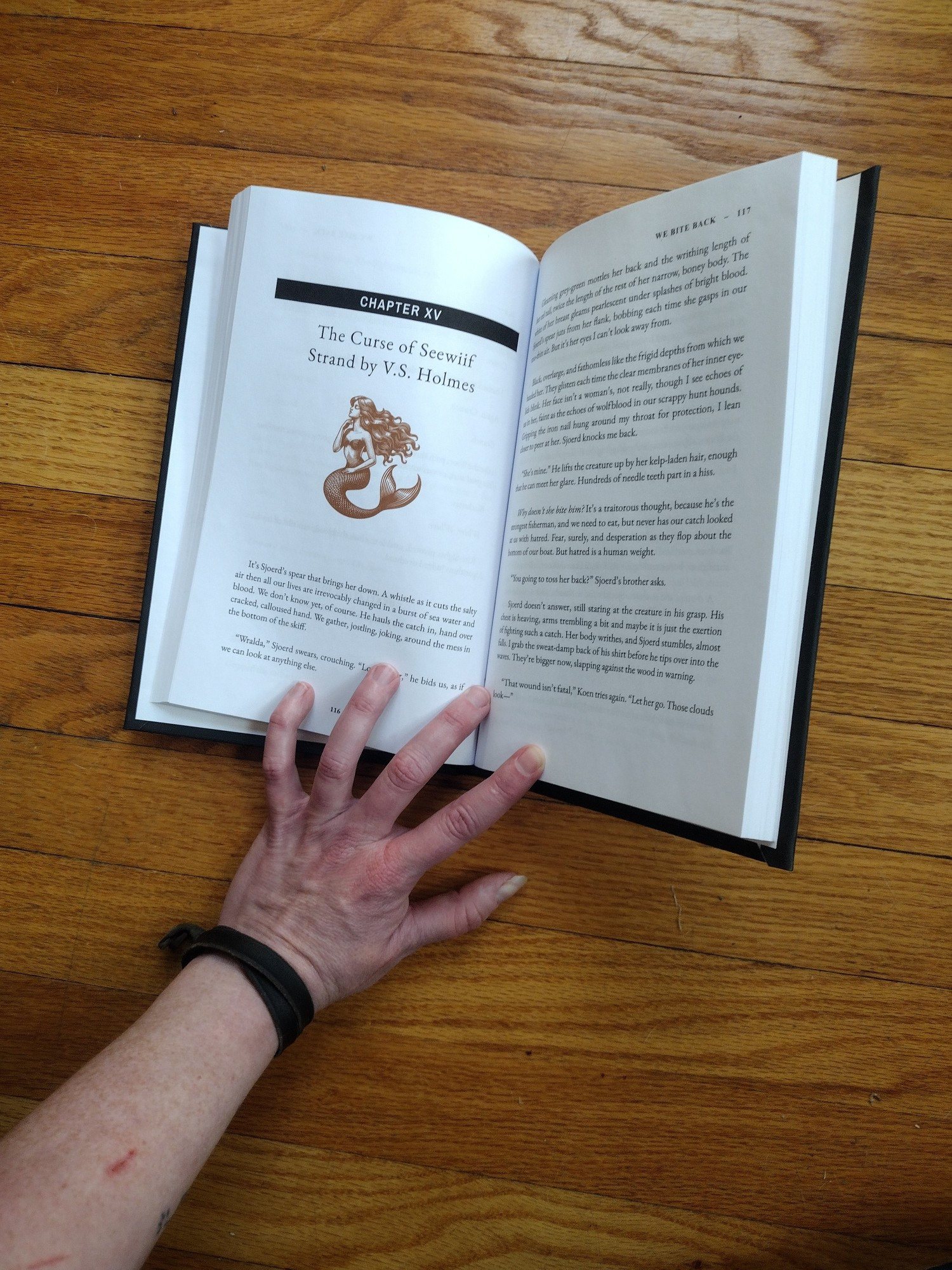 The interior of WE BITE BACK showing my story "The Curse of Seewiif Strand" by V. S. Holmes. The chapter art is a copper colored classic woodcut style mermaid. 
