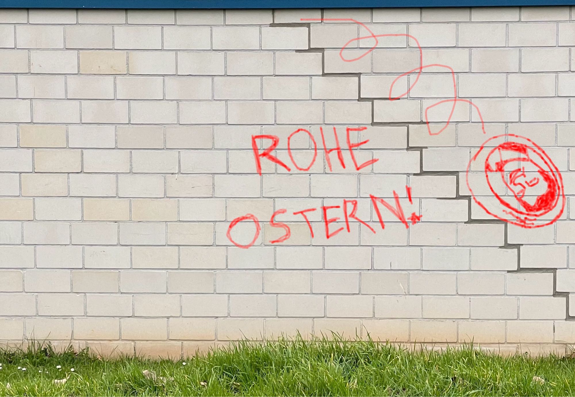 Eine Mauer, bei der in der rechten Hälfte der Mörtel zwischen den versetzten weißen Steinen in Form einer nach unten führenden Treppe betont ist. Darauf habe ich mit einem Bildbearbeitungsprogramm ein "Graffiti" gesprüht: Das Markus-Söder-Osterei kullert die Treppe herunter, und links von der Treppe steht "ROHE OSTERN!"