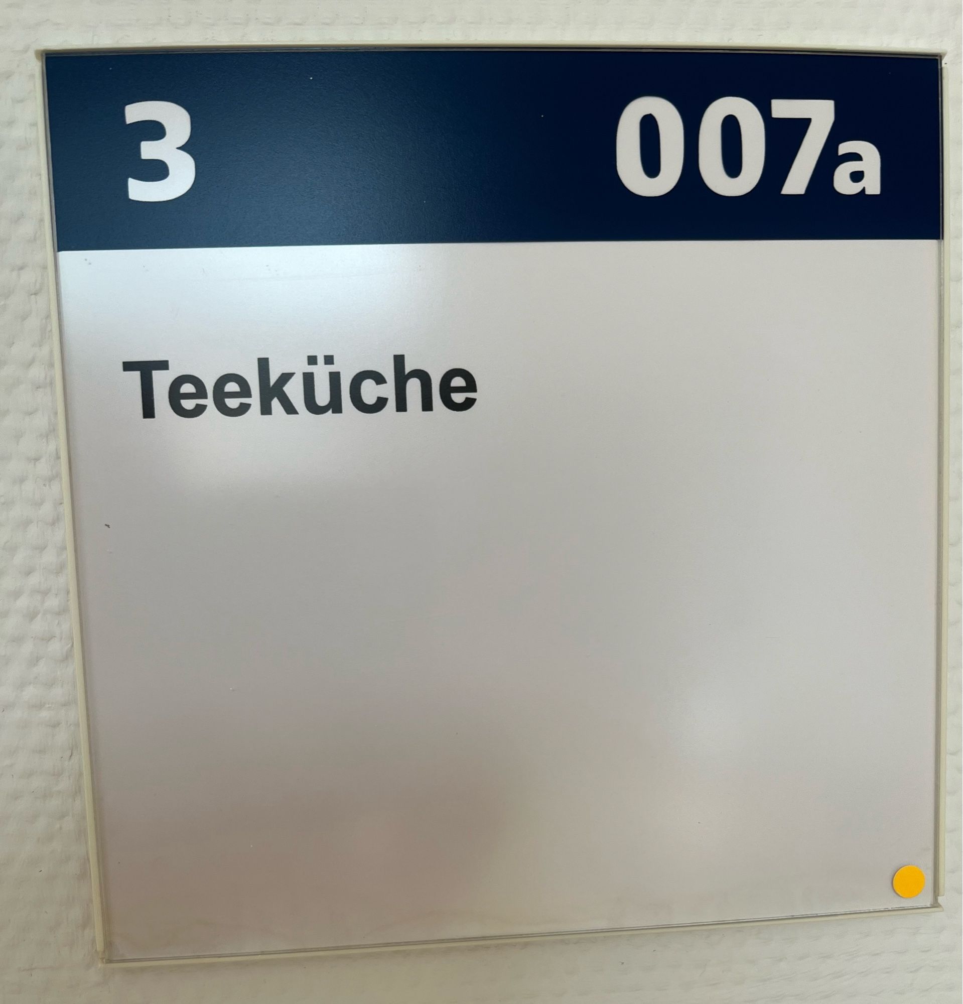 Ein Schild neben einer (nicht im Bild gezeigten) Tür: “3 - 007a - Teeküche”