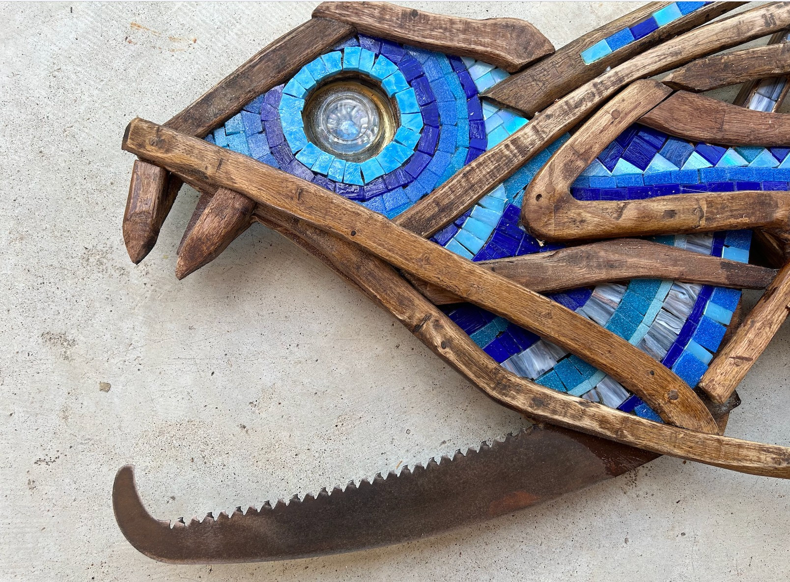 Closeup of fish head;
eye is made of an old candle holder backed with mosaic iris surrounded by gold leaf.