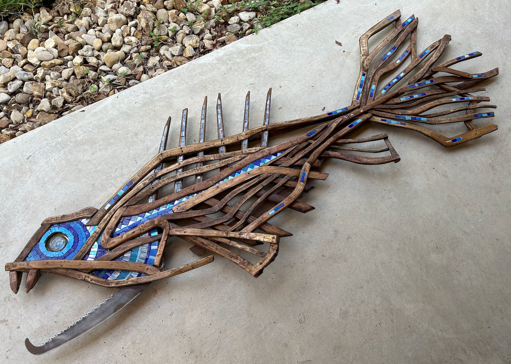 Wallfish lying on concrete path (78" x 28")
Split oak branches and scrap wood, old pruning saw blade, inset mosaic tiles in  iridescent blues