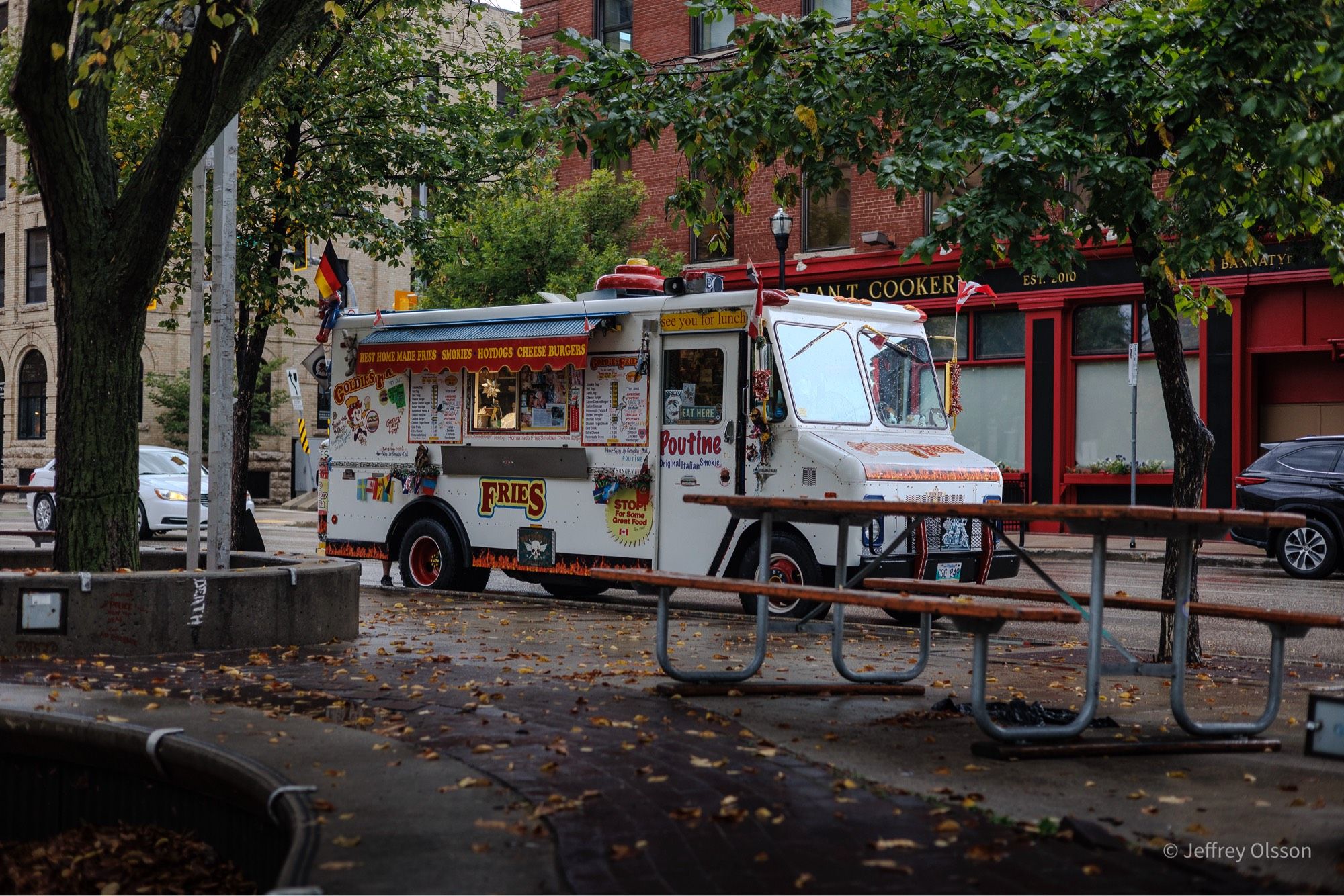 A German fry truck waits patiently for customers on a rainy day. The light reflects off of the wet truck.