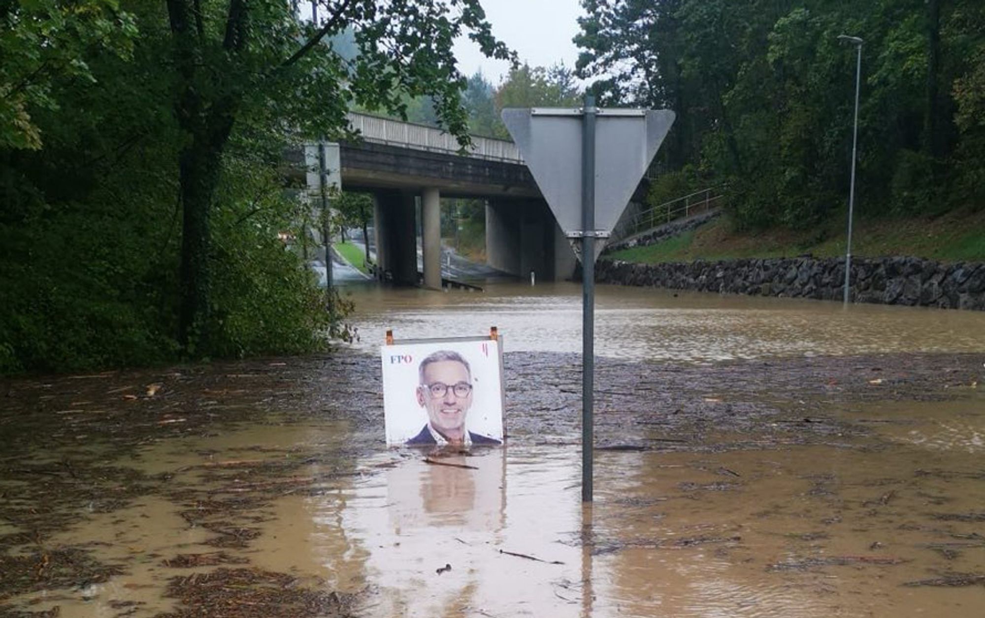 Foto einer überschwemmten Unterführung mit braunem Wasser. Darin steht ein Wahlplakat von Kickl FPÖ. Quelle: bluesky/ Unbekannt