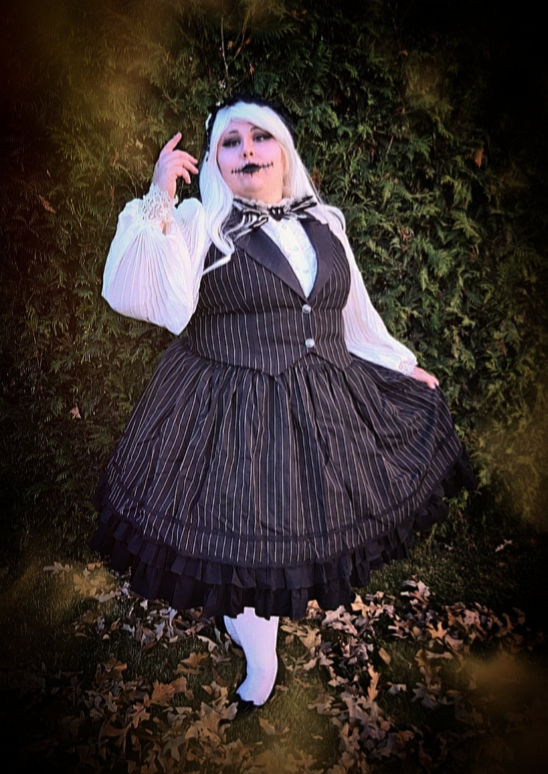 Plus size girl dressed as a girl version of jack skellington with a black skirt with thin white line and a matching vest and a white blouse and a white wig and a skelleton makeup