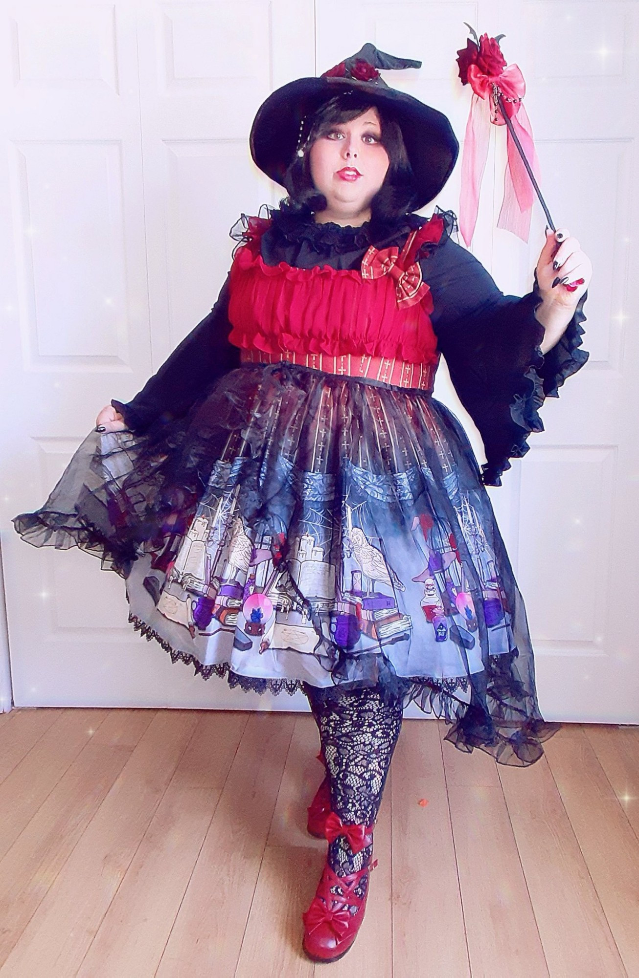 Plus size white girl dressed as a witch with a knee-lenght frilly dress with books , potion and white owls on it and a black witch hat and a wand with roses and bat wings on it 