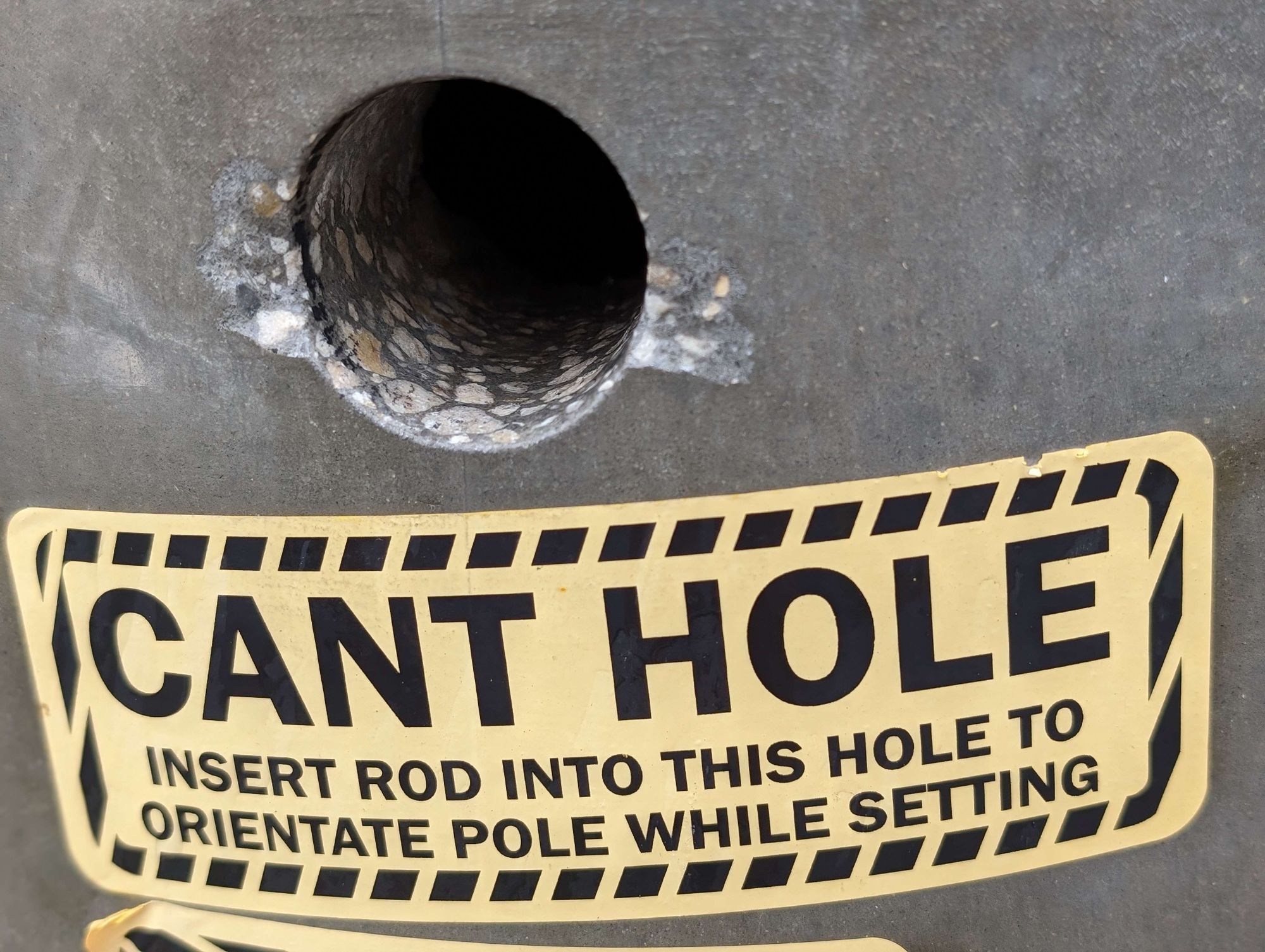 "can't hole" sticker saying 'insert rod into this hole to orientate pole while setting' on a new telephone pole