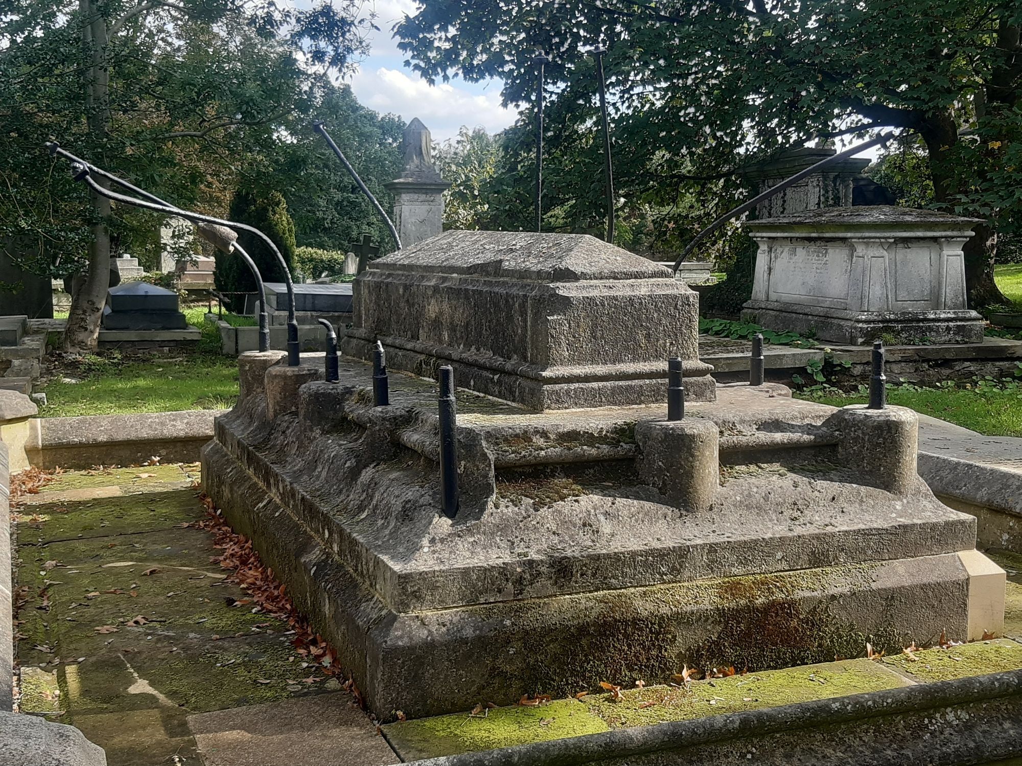 A grave in West Norwood Cemetery with iron support arms for a missing top piece wrenched away by unseen forces and opened up like a giant rib cage around the grave