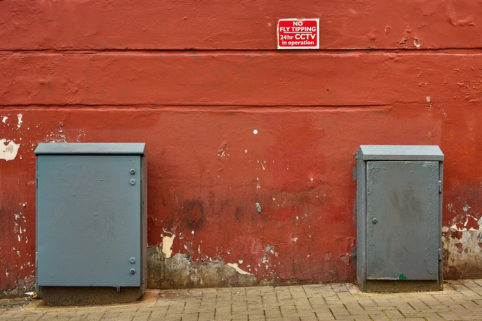 Red wall with utility boxes in West Norwood, London