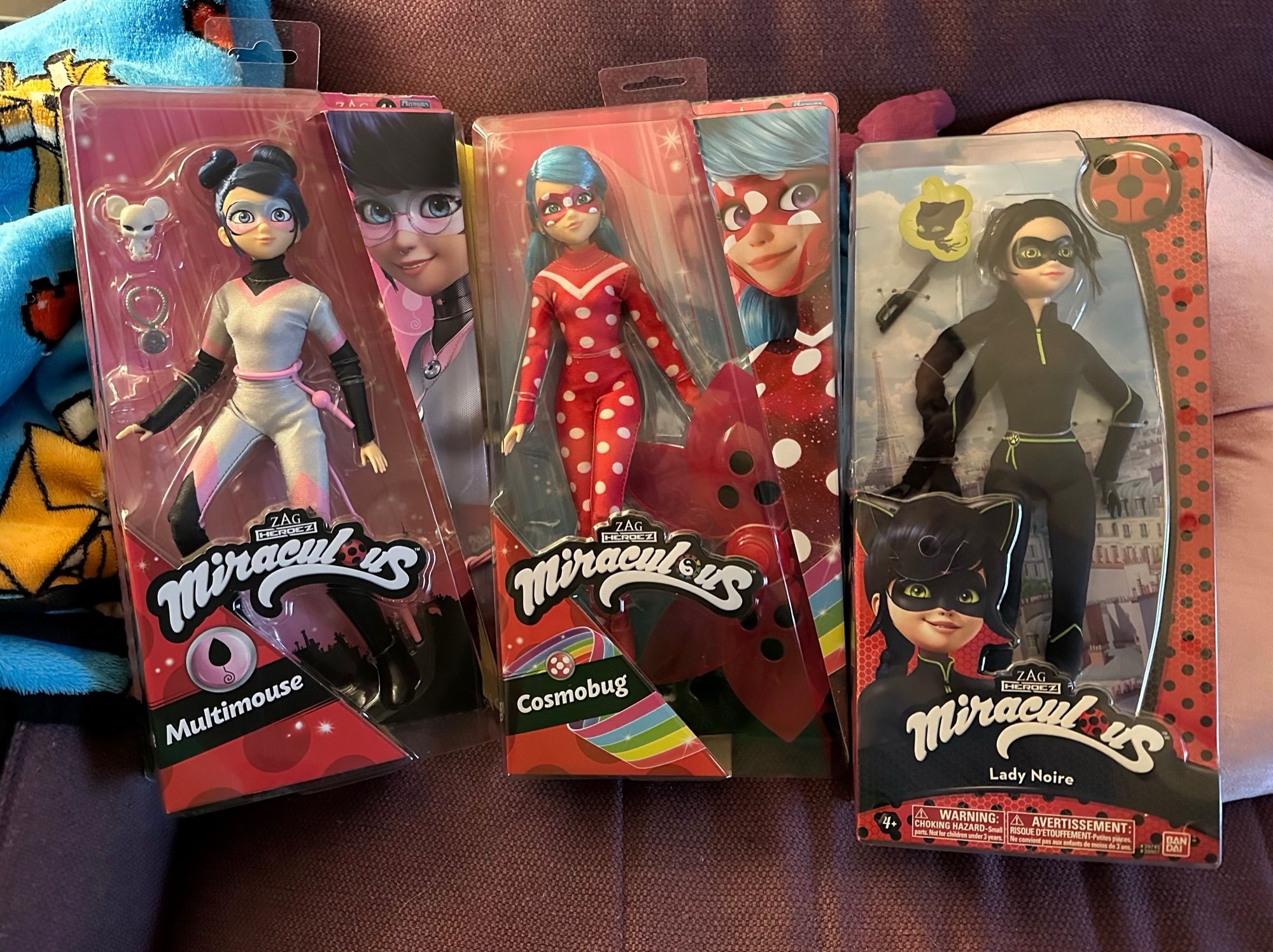 Miraculous Ladybug dolls laid out on a couch. From left to right, there’s Multimouse, Cosmobug, and Lady Noire.