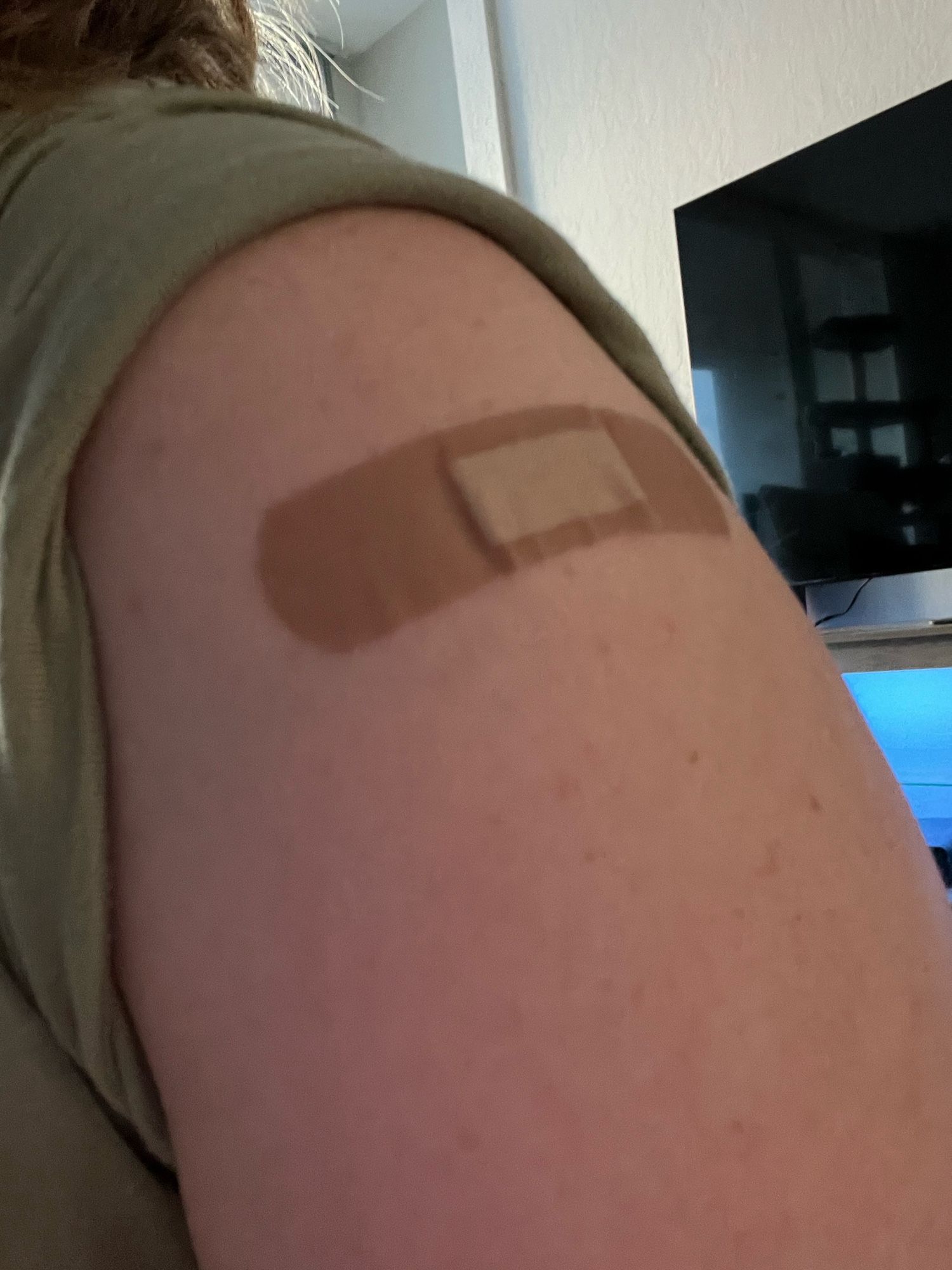 A left upper arm with a band aid.