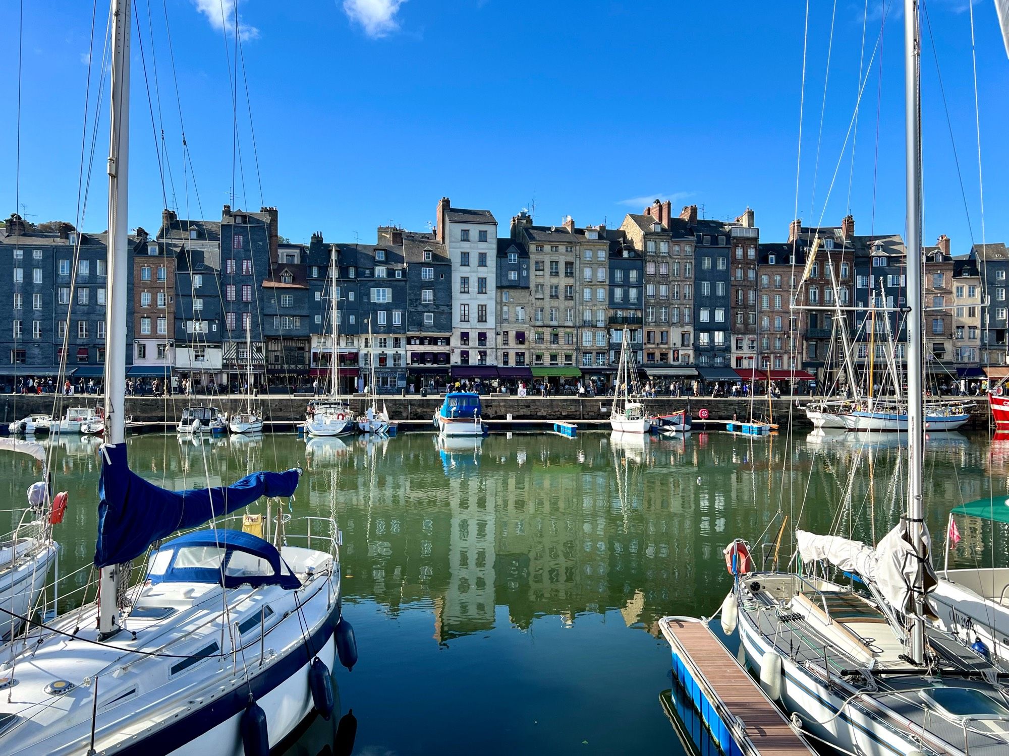 Vieux bassin de Honfleur avec des bateaux et le reflet des immeubles colorés dans l’eau