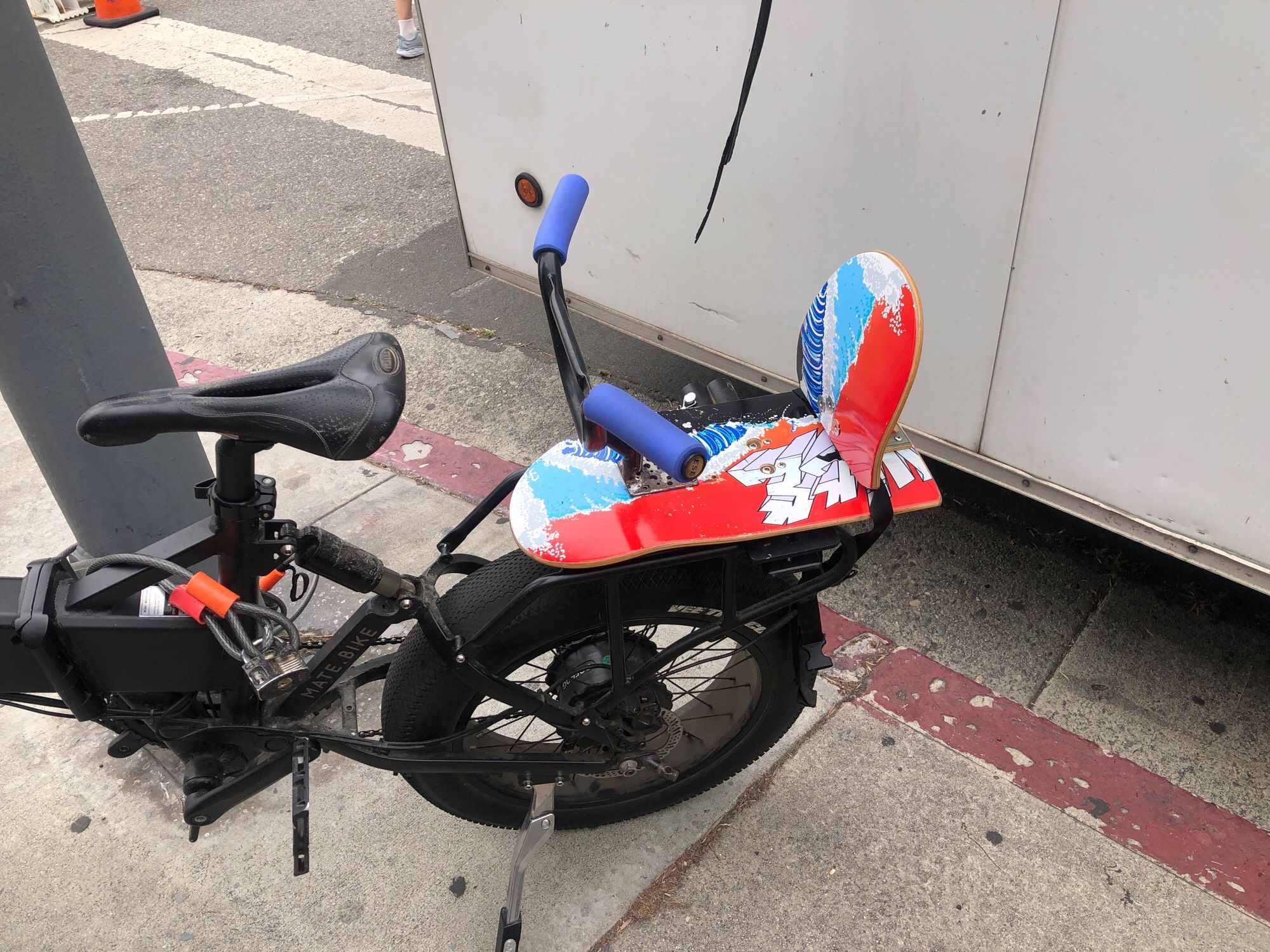 Child seat on rear rack of ebike made from a skateboard and shortened BMX bars