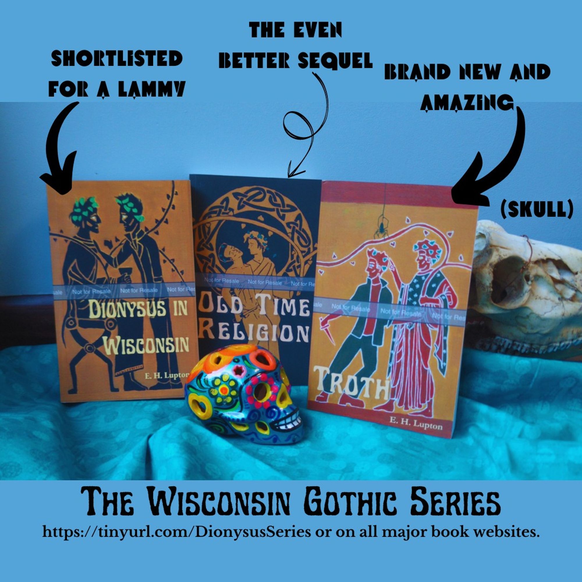 Three proof copies of books leaning against a deer skull with a Mexican sugar skull (actually clay, but brightly painted with flowers) standing in front of them. There’s text above the books with arrows pointing at them. The books are Dionysus in Wisconsin (text above: Shortlisted for a Lammy), Old Time Religion (text above: the even better sequel), and Troth (brand new and amazing). There’s a label above the deer skull that says “skull.” Below, it says “The Wisconsin Gothic Series: https://tinyurl.com/DionysusSeries or on all major book websites.