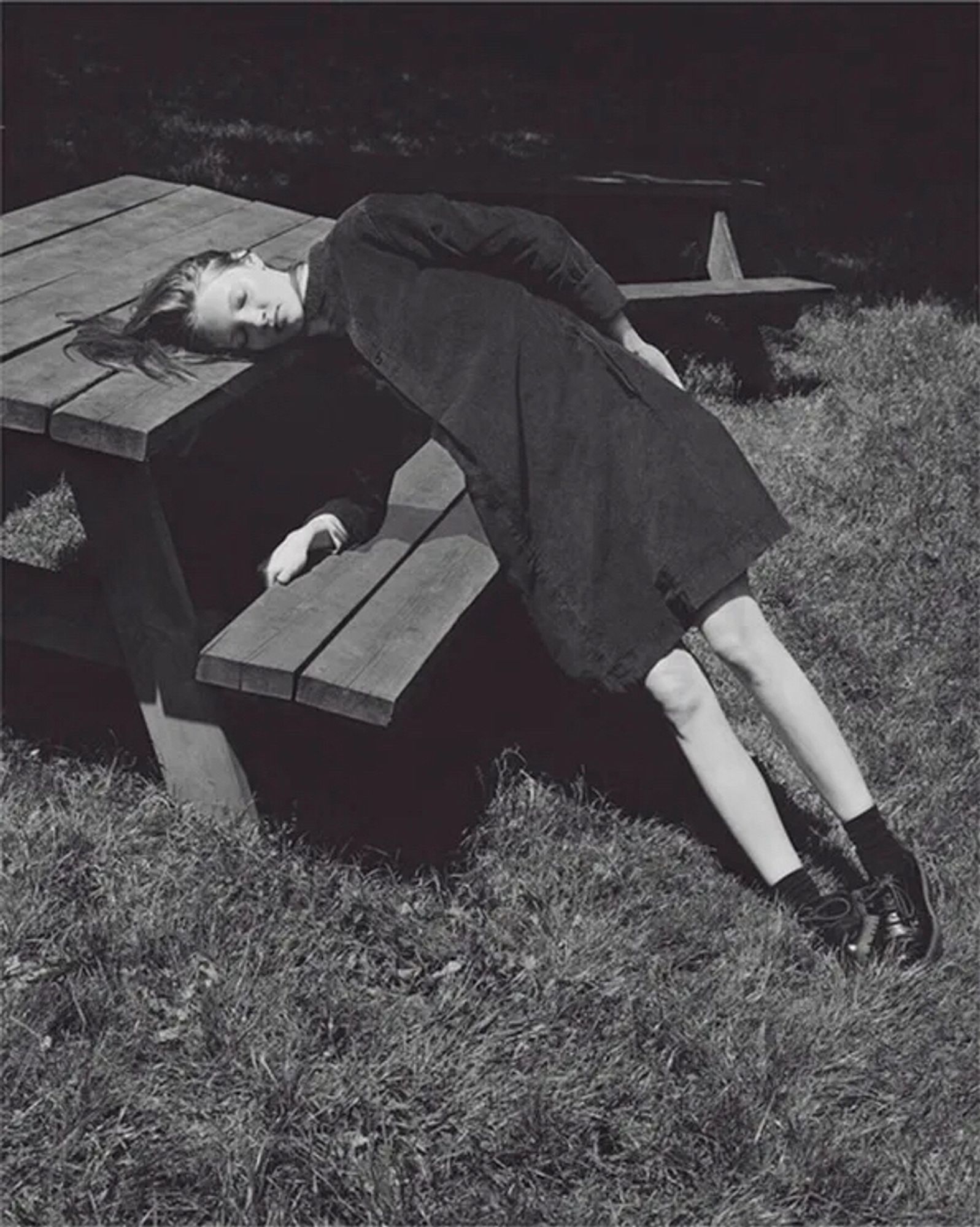 Black & white photo by Alice Goddard.
A woman leaning on a wooden park table bench, her head on the table.