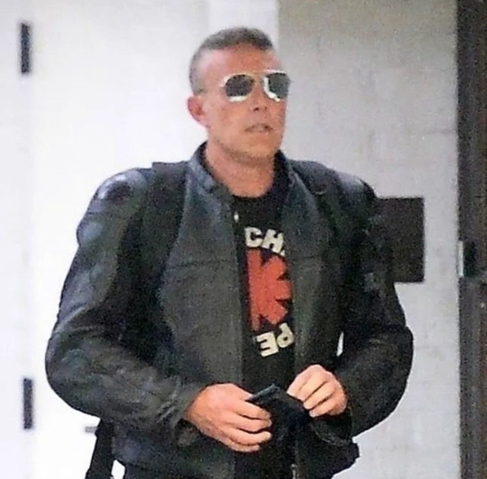 Ben affleck in a leather jacket and RHCP shirt, his head shaved into a fauxhawk