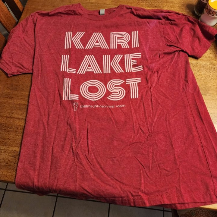 A red Kari Lake Lost t shirt lovingly displayed on a table.