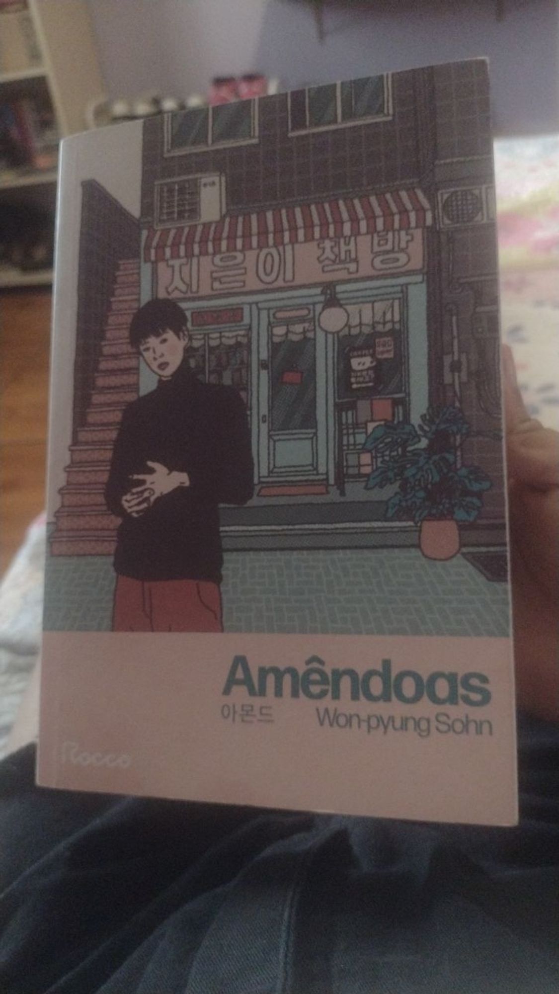 Capa do livro "Amêndoas", de Won-pyung Sohn.
O protagonista, Yunjae, está na frente de uma livraria.