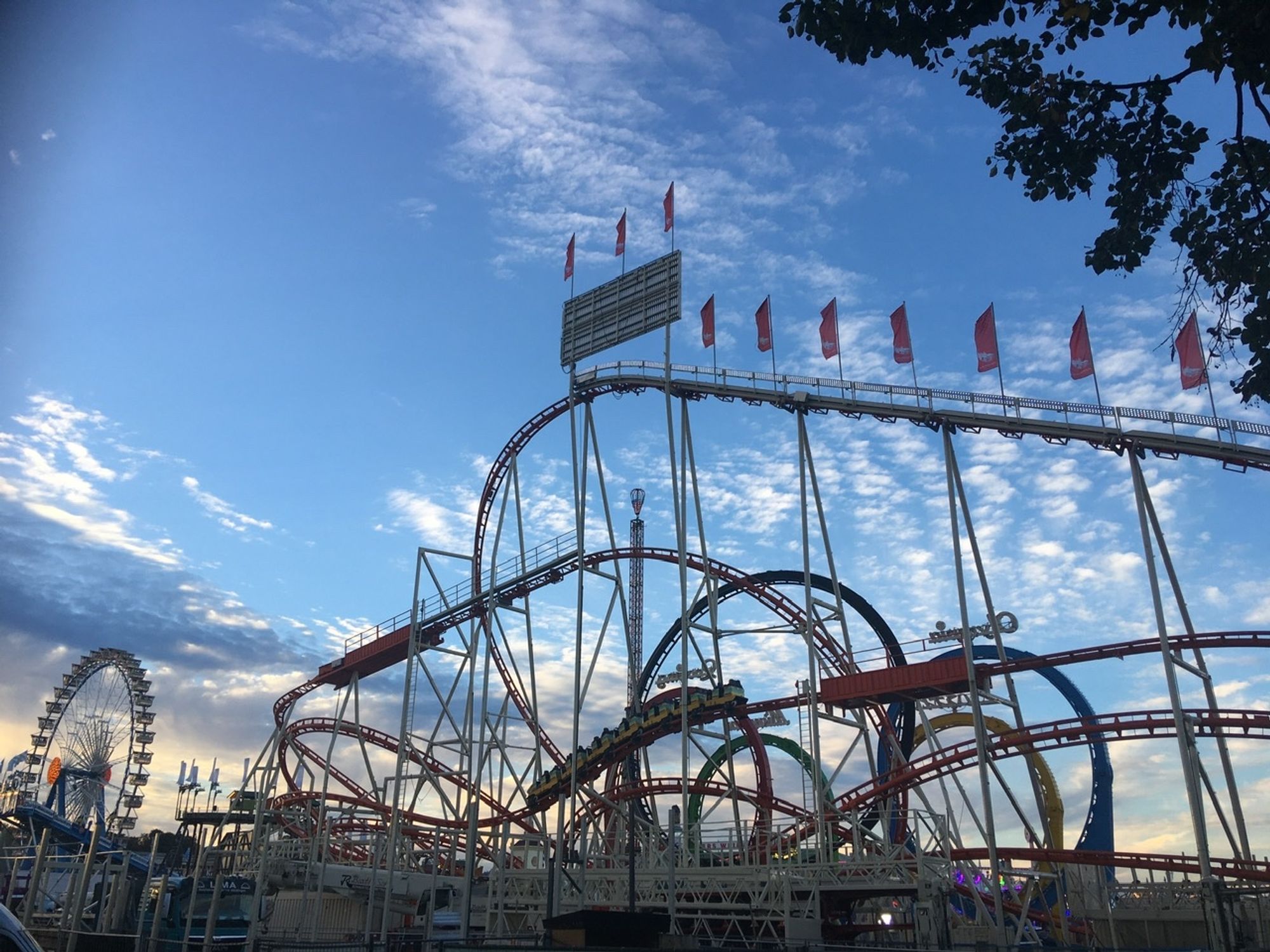 Riesenrad und Fünfer- Looping unter dem abendlichen Wiesn-Himmel